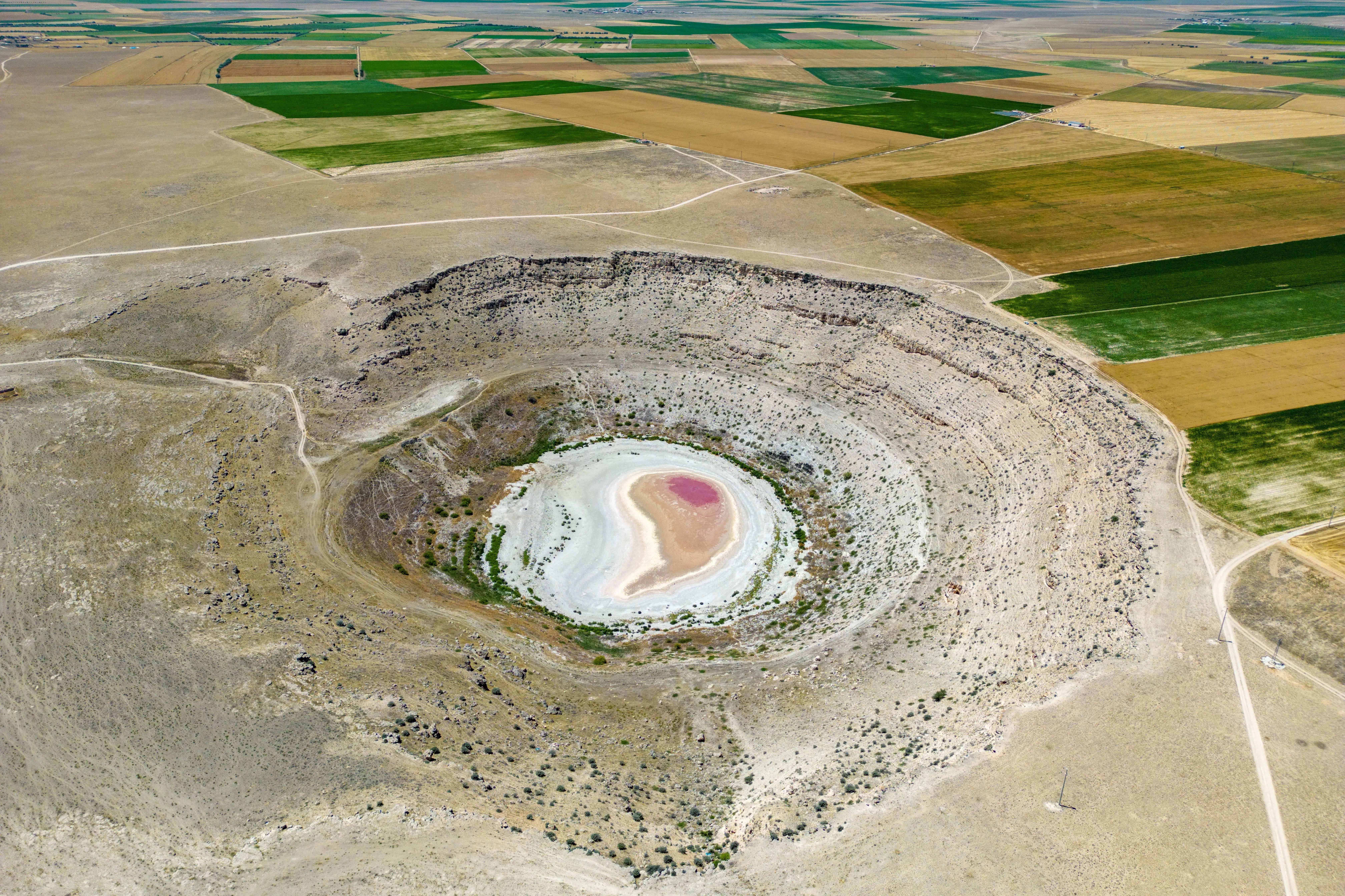 فوهة جافة محاطة بأراض زراعية، تشير إلى تأثير الإفلاس المائي العالمي وتدهور البيئة، كما ورد في تقرير الأمم المتحدة.