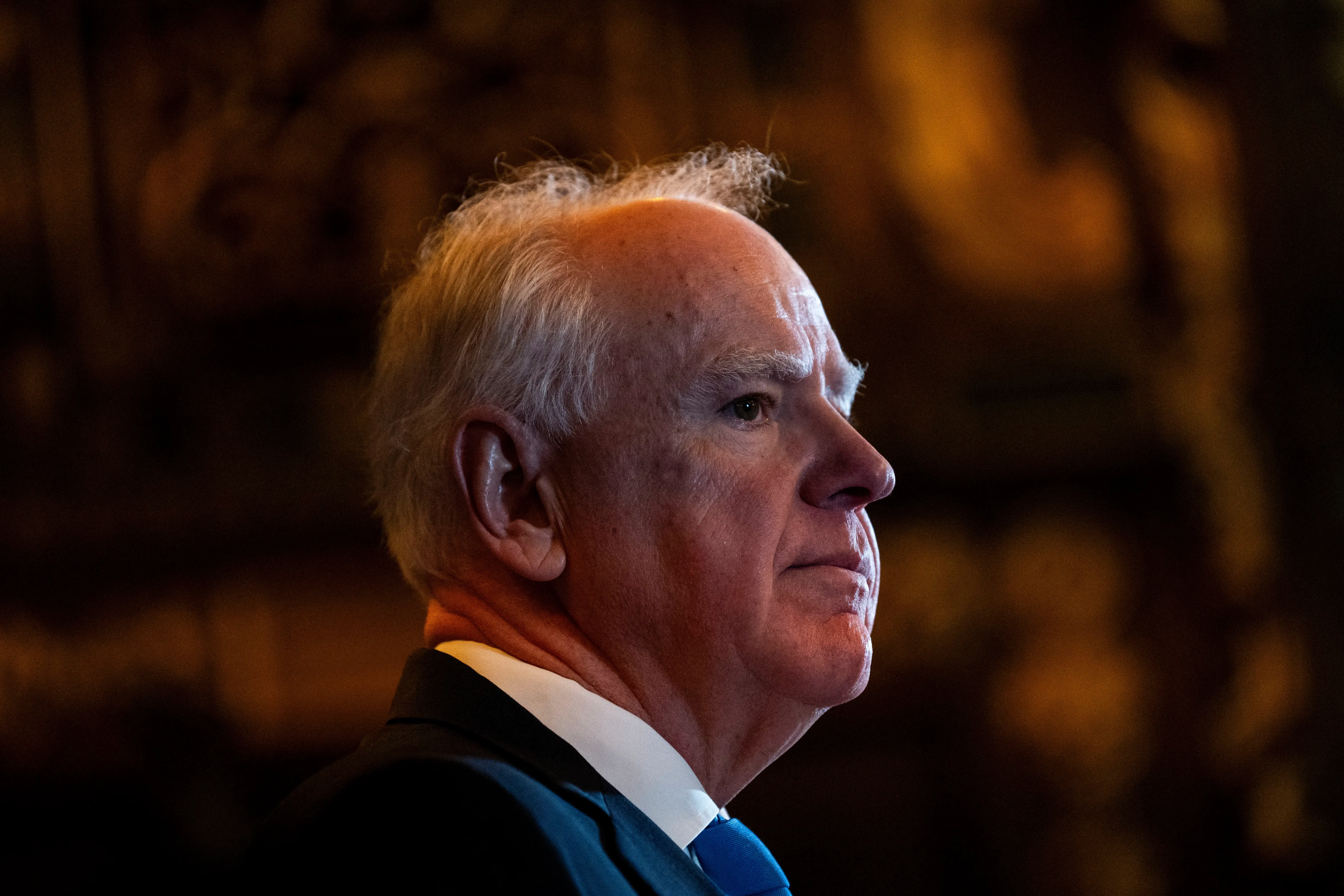 صورة لرجل مسن ذو شعر رمادي، يبدو عميق التفكير، في بيئة مضاءة بشكل خافت، تعكس أجواء سياسية مشحونة.