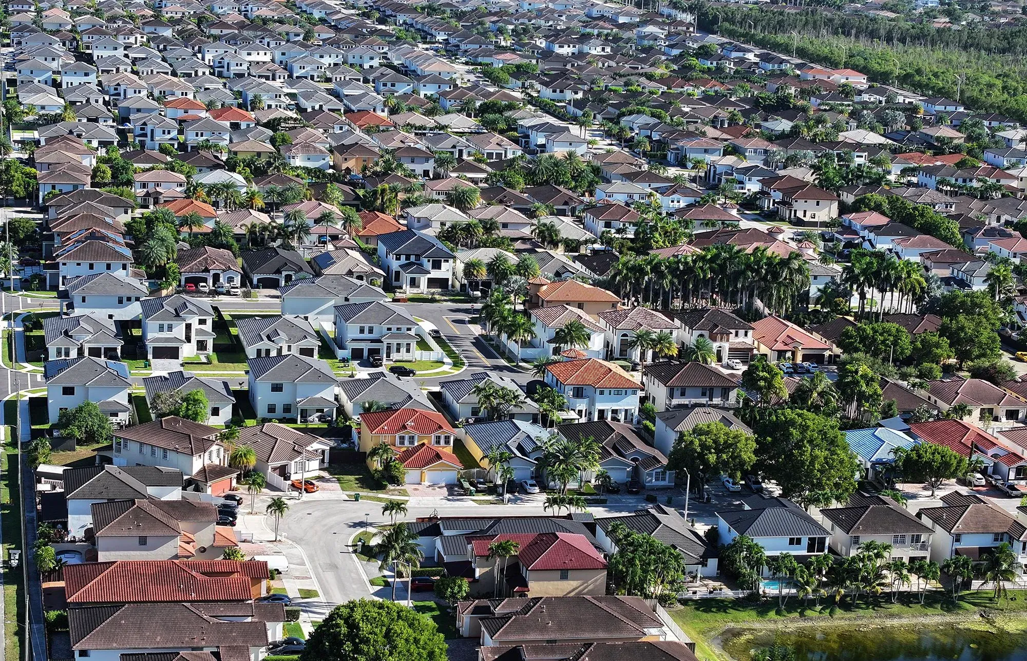 صورة جوية لحي سكني يحتوي على منازل متعددة الطوابق، مع حدائق وأشجار، تعكس أزمة الإسكان وارتفاع تكاليف المعيشة في الولايات المتحدة.