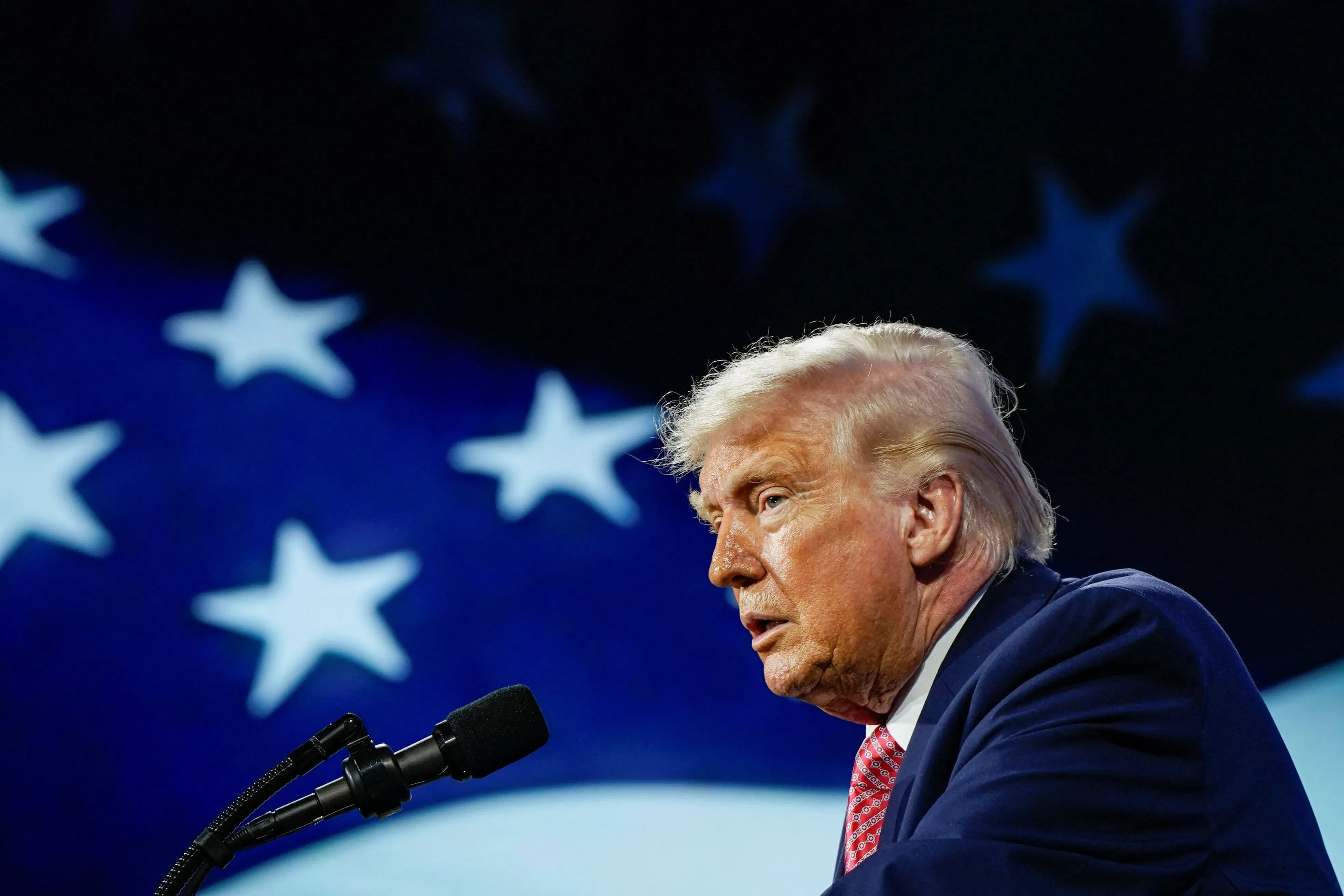 خطاب للرئيس ترامب أمام خلفية علم الولايات المتحدة، حيث يعبر عن مواقفه المتضاربة بشأن الحرب في إيران ويدعو إلى السلام.