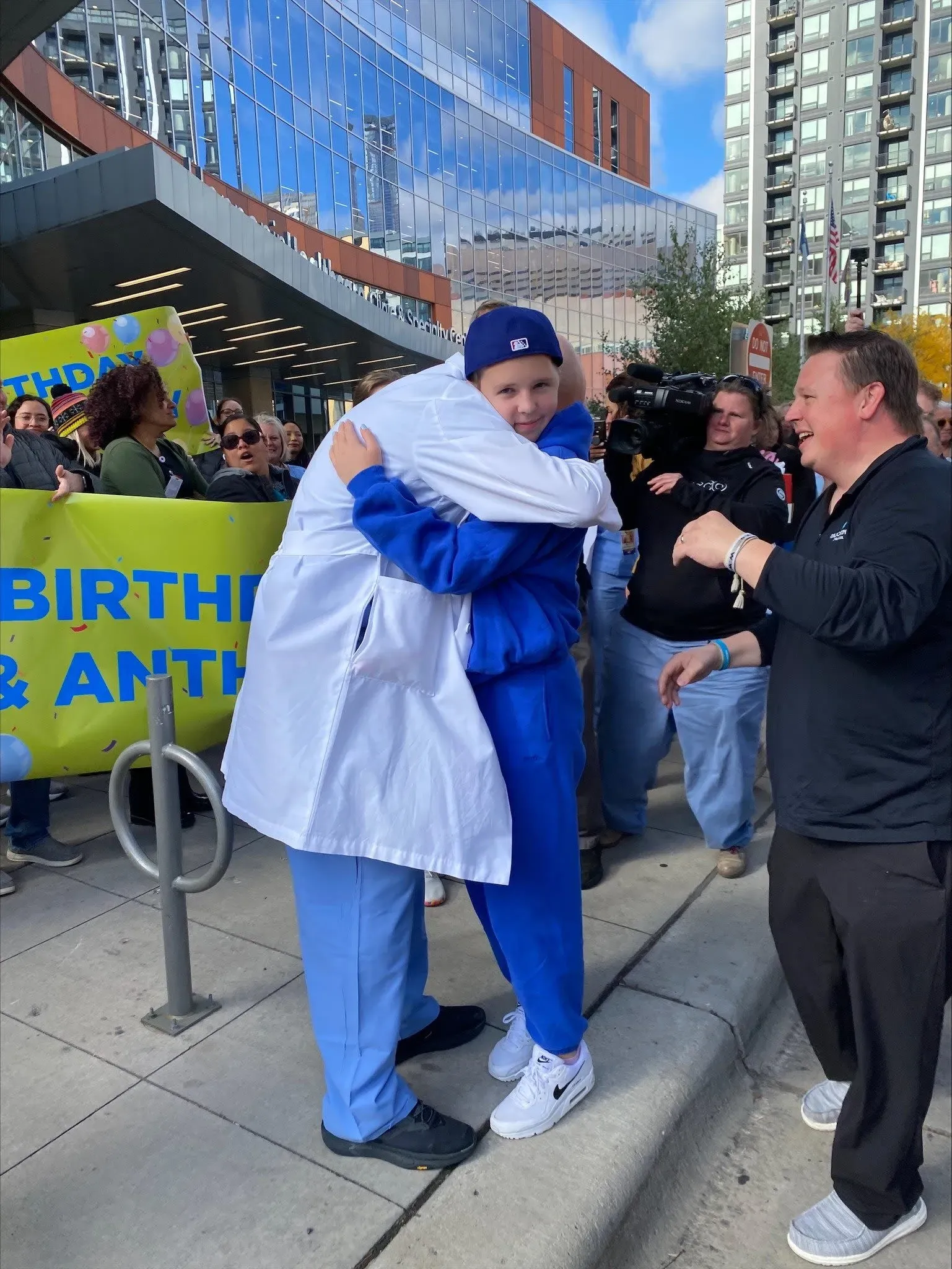 صوفيا فورتشاس، الفتاة التي نجت من إطلاق نار، تحتضن طبيبها أمام حشد من المحتفلين في مينيابوليس، مع لافتات تهنئة بعيد ميلادها.