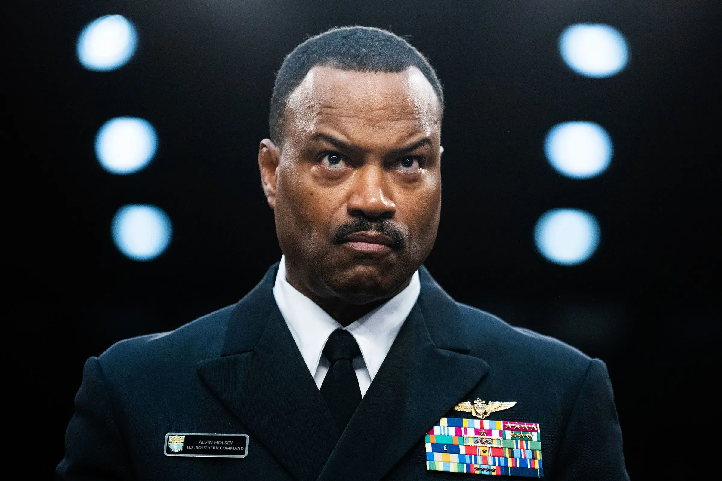 الصورة تظهر ضابطًا عسكريًا أمريكيًا يرتدي زيًا رسميًا، مع شارات على صدره، يعبر عن جدية في تعبير وجهه.