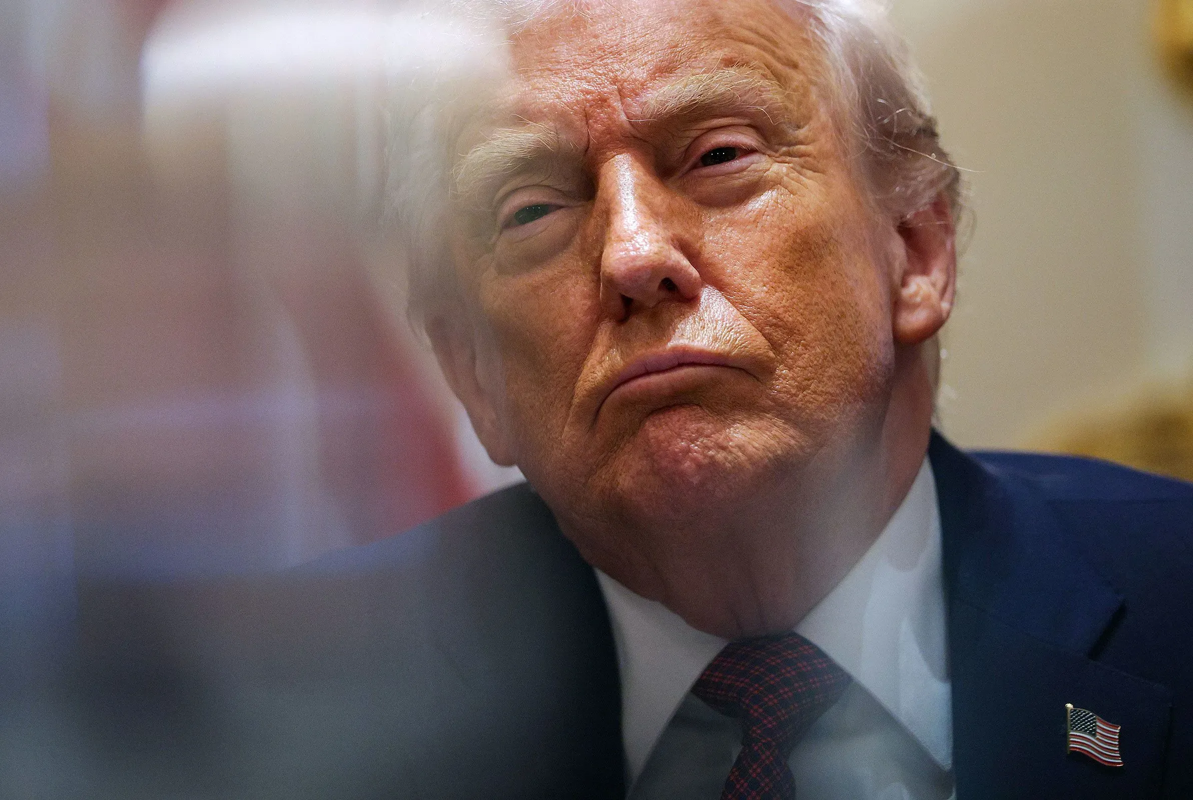 صورة مقربة لدونالد ترامب، يظهر فيها تعبير وجهه الجاد أثناء اجتماع، مع خلفية ضبابية تعكس الأجواء السياسية المتوترة.