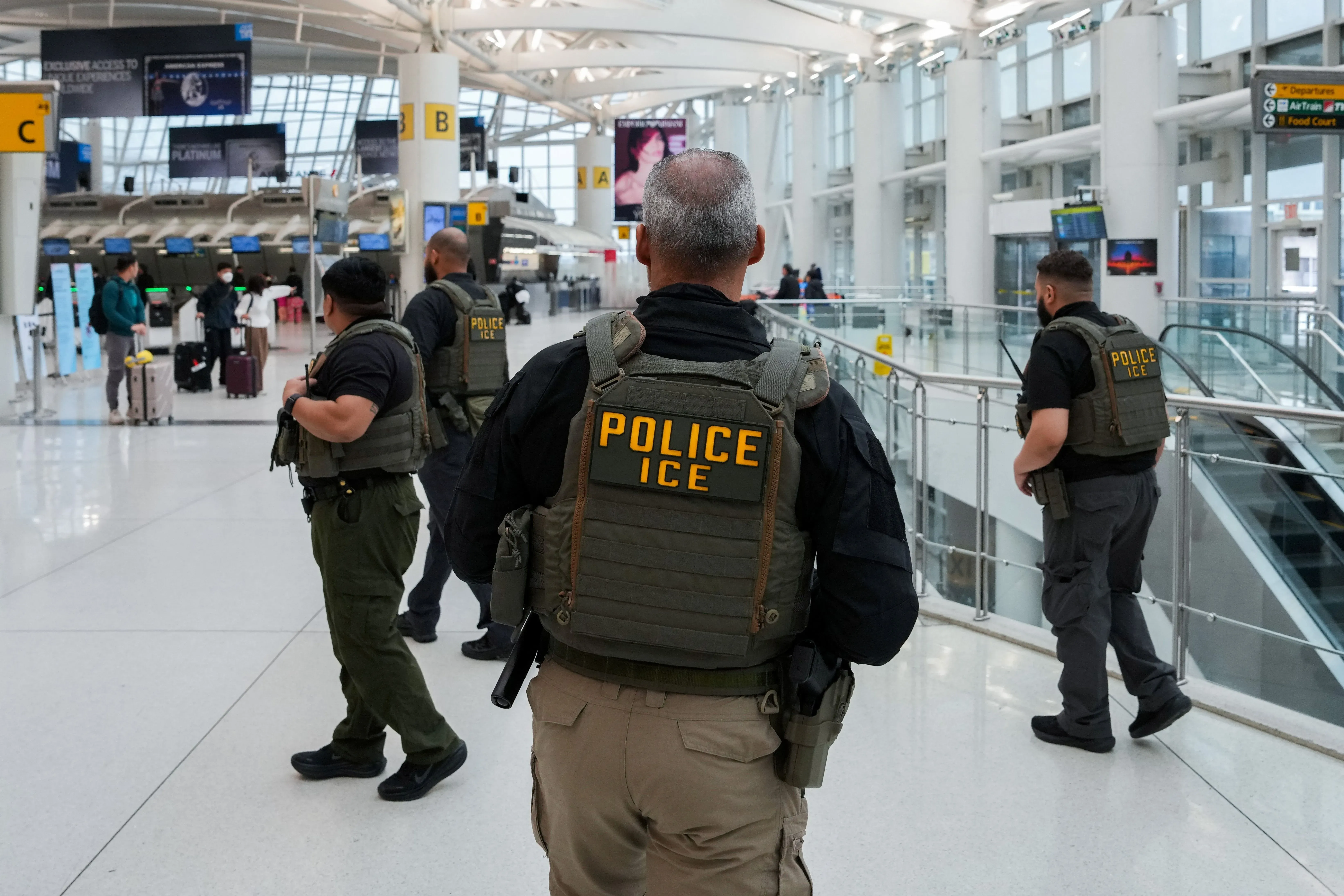 زيادة الوجود الأمني في مطار، حيث يظهر عدد من ضباط الشرطة يرتدون سترات تحمل علامة "POLICE ICE"، وسط أجواء من الازدحام.