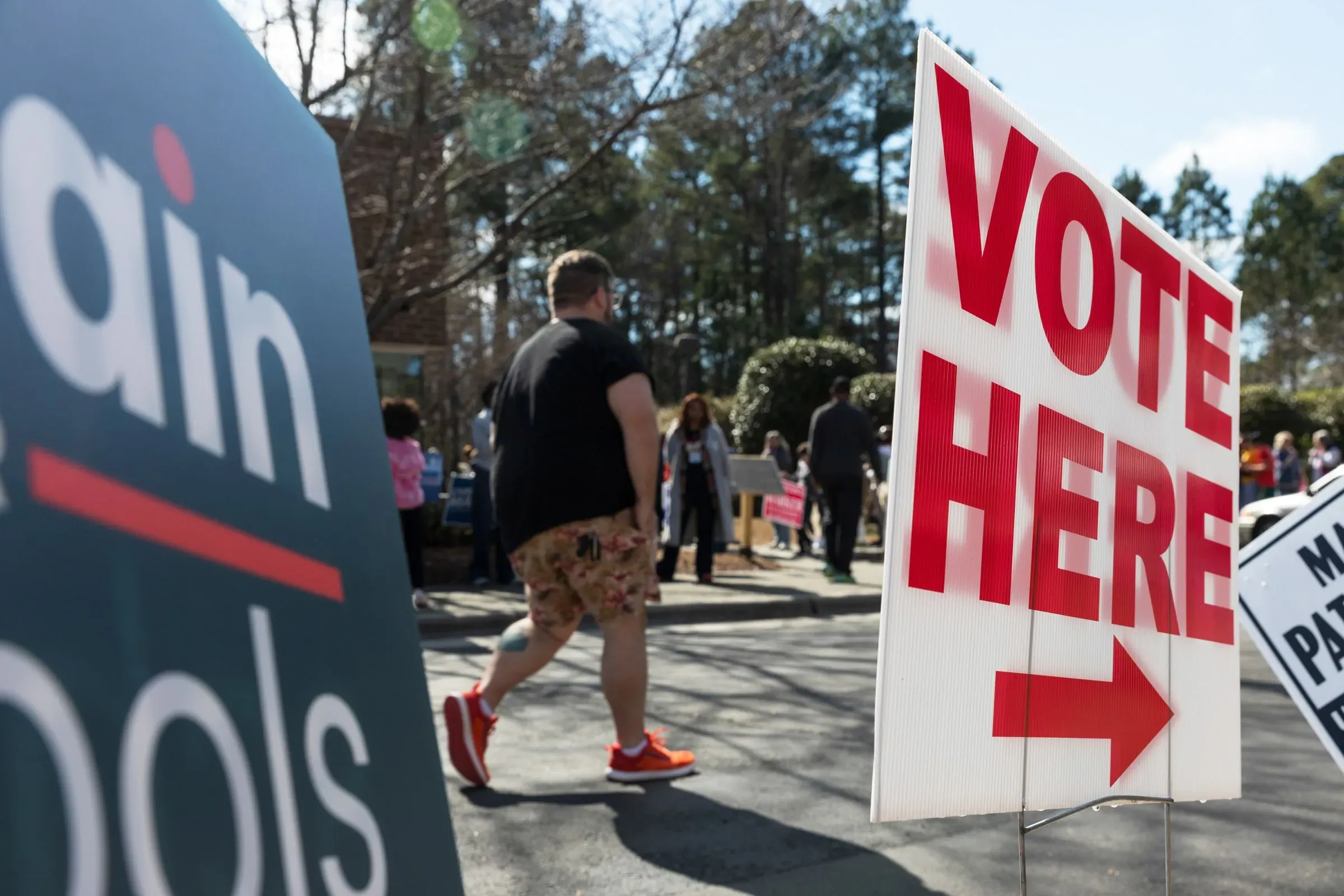 لافتة كبيرة تشير إلى مكان الاقتراع مع وجود ناخبين يتوجهون نحوها، مما يعكس أهمية الانتخابات التمهيدية في تكساس.