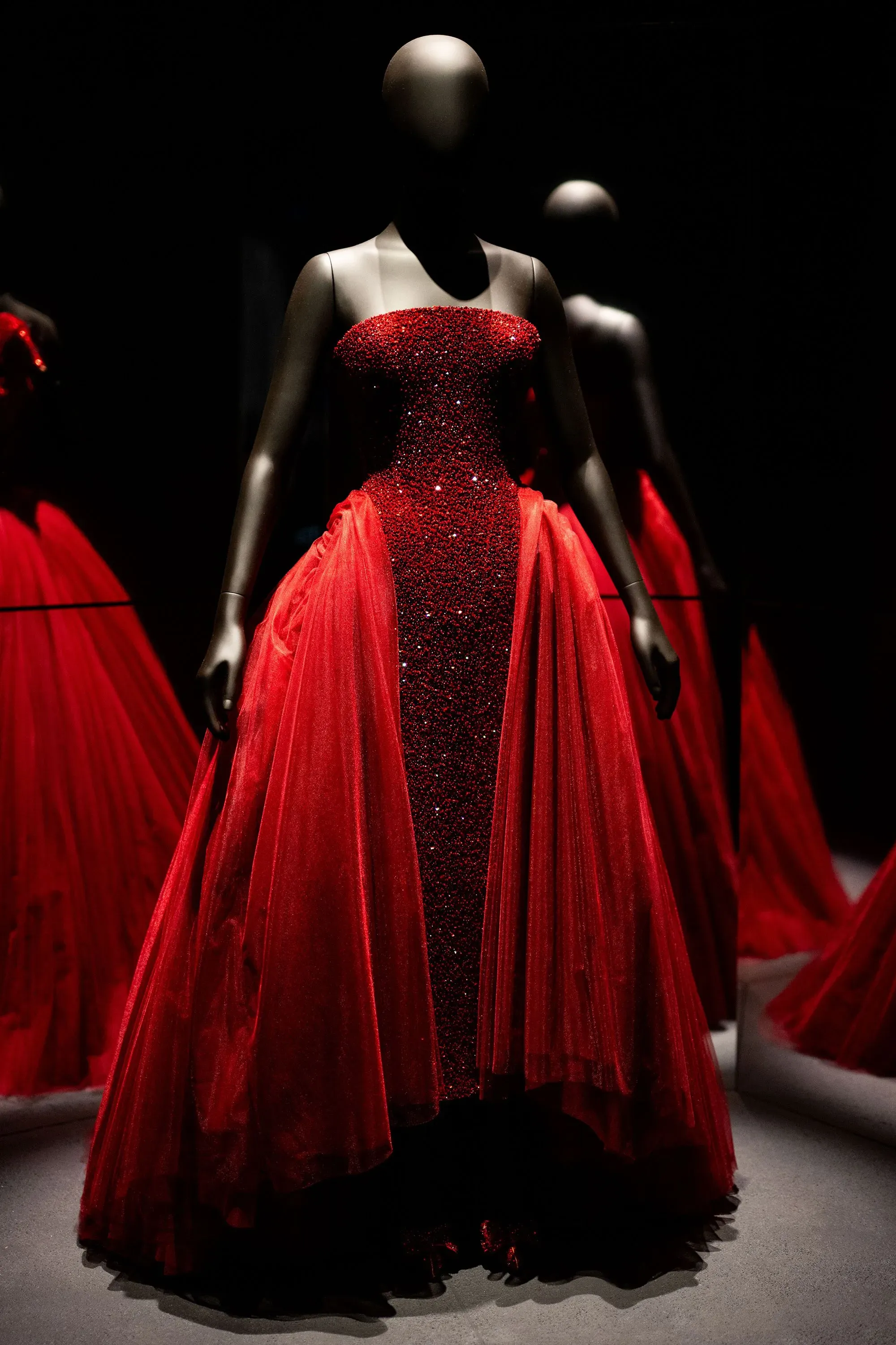 فستان أحمر مزين بالخرز، يعكس جمالية تصميم إلسا سكياباريللي، معروض في معرض "سكياباريللي: الموضة تصبح فناً" بمتحف فيكتوريا وألبرت بلندن.