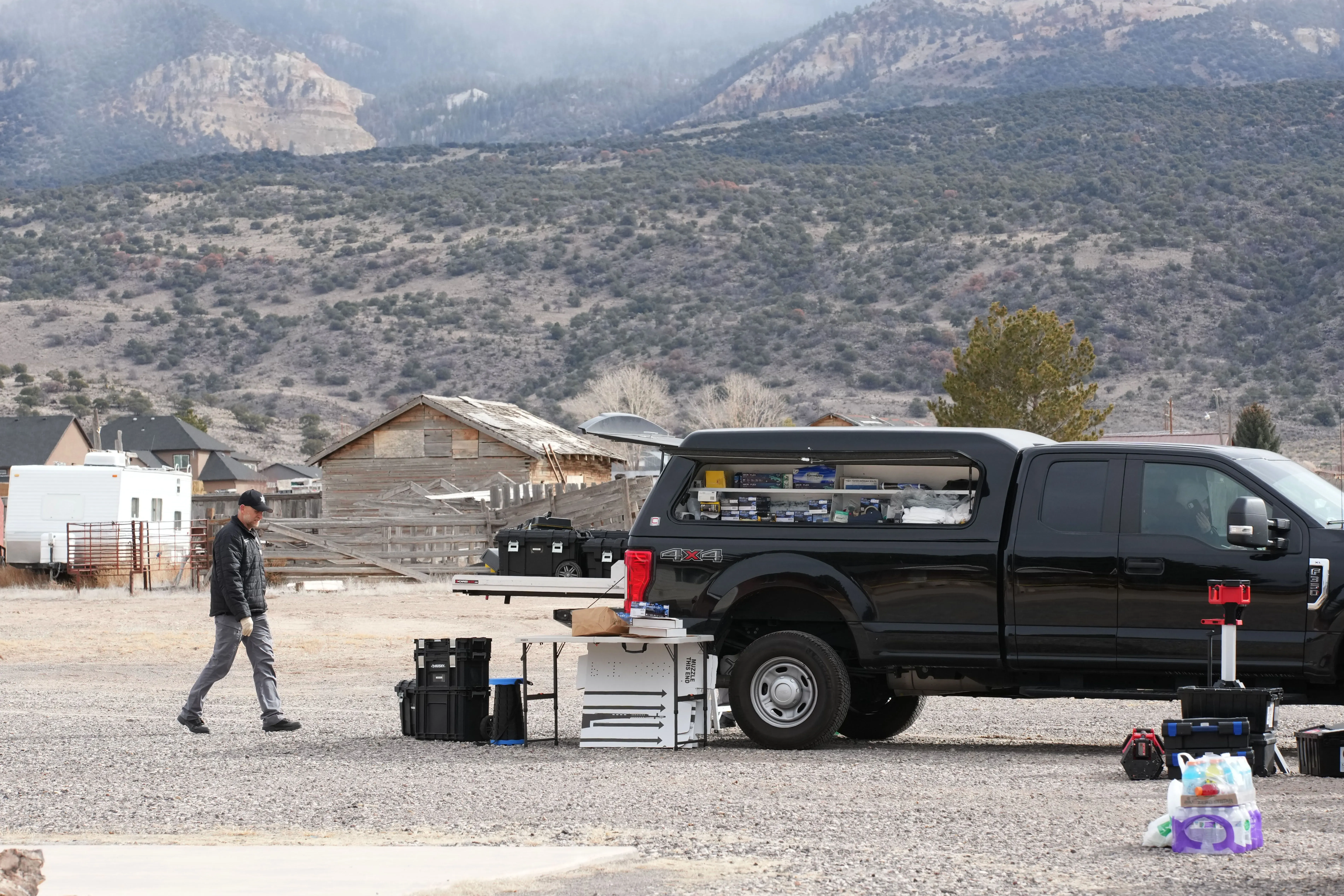 رجل يسير بالقرب من شاحنة سوداء في منطقة ريفية بولاية يوتا، حيث تجري التحقيقات في جرائم قتل متعددة.