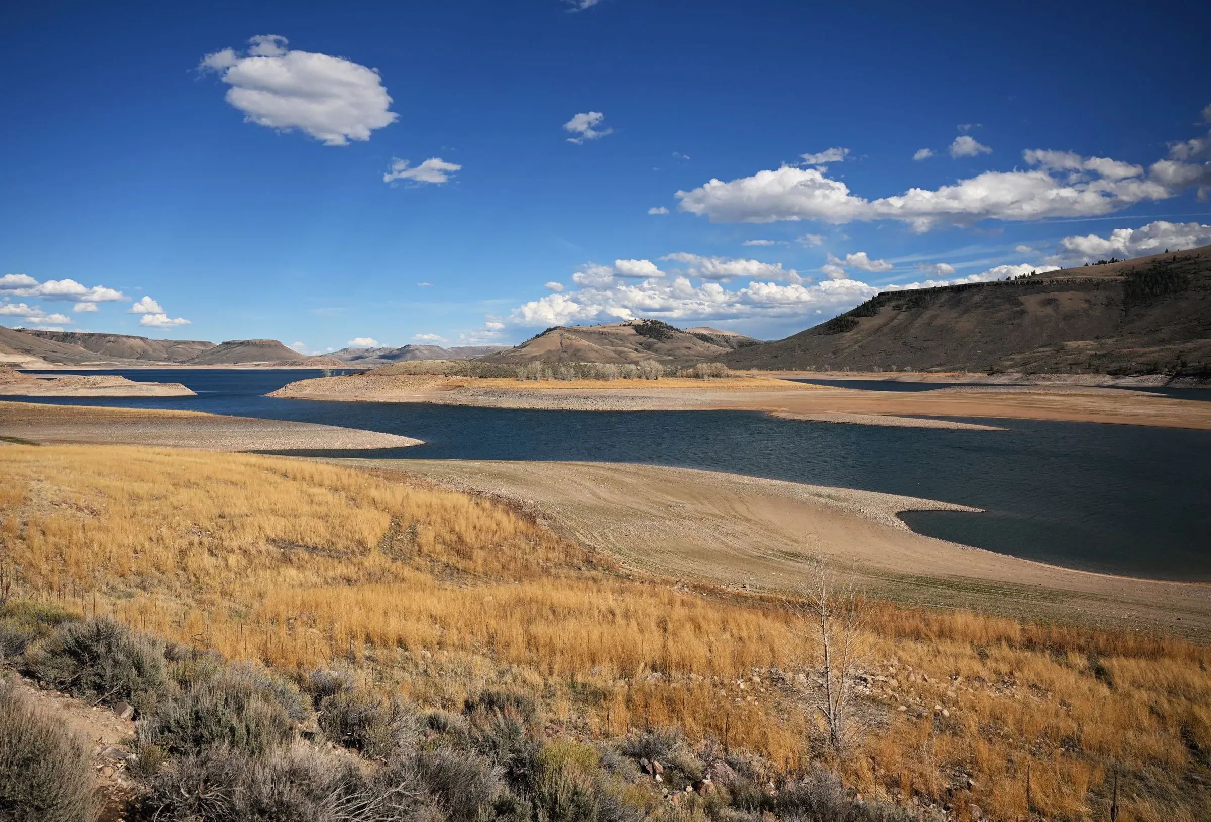 منظر طبيعي في كولورادو يظهر بحيرة جافة محاطة بأراضٍ جافة وأعشاب صفراء، مما يعكس تأثير الجفاف الشديد على المنطقة.