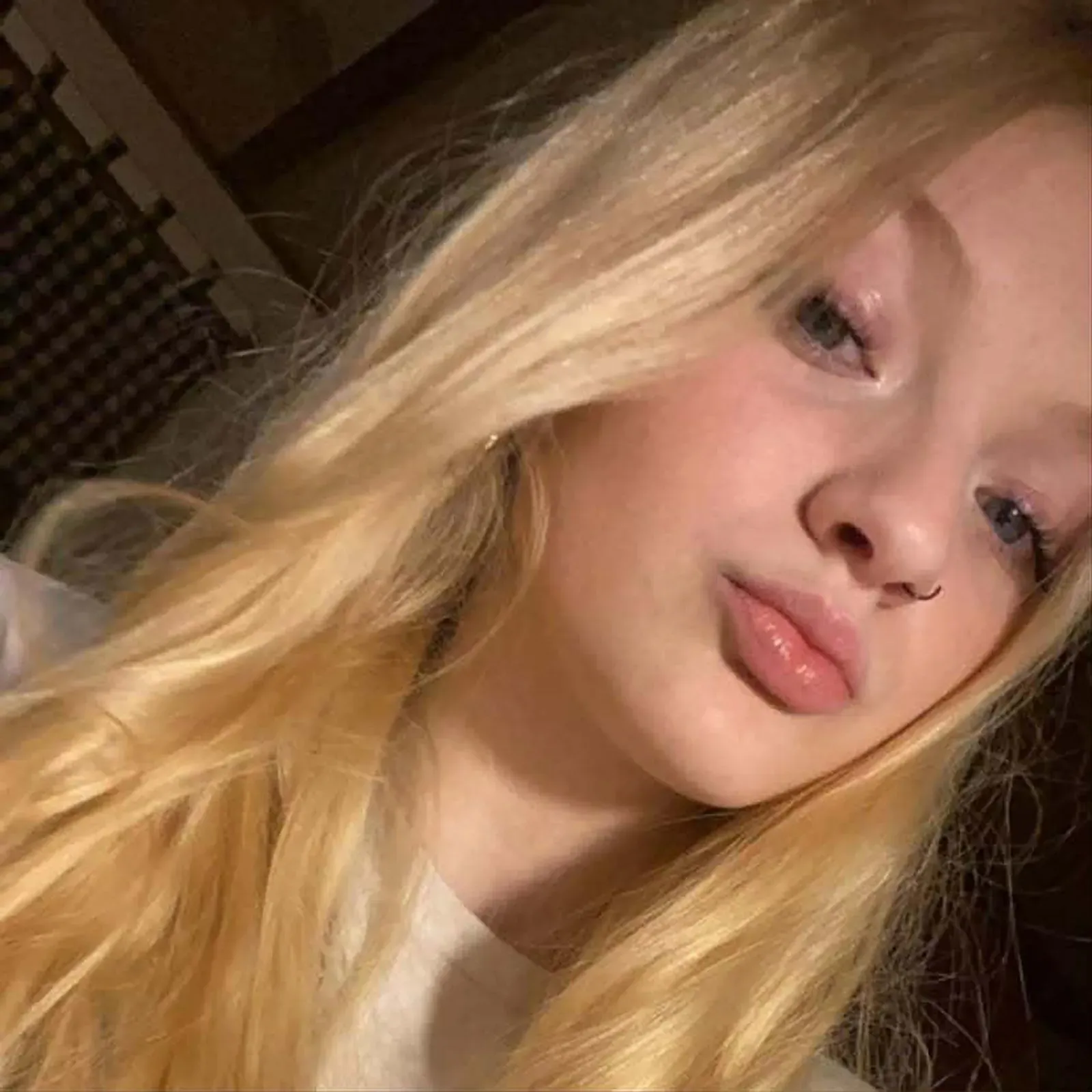 صورة لفتاة شابة ذات شعر أشقر طويل، تبتسم برفق، تعكس لحظة من الأمل بعد مأساة عائلتها.