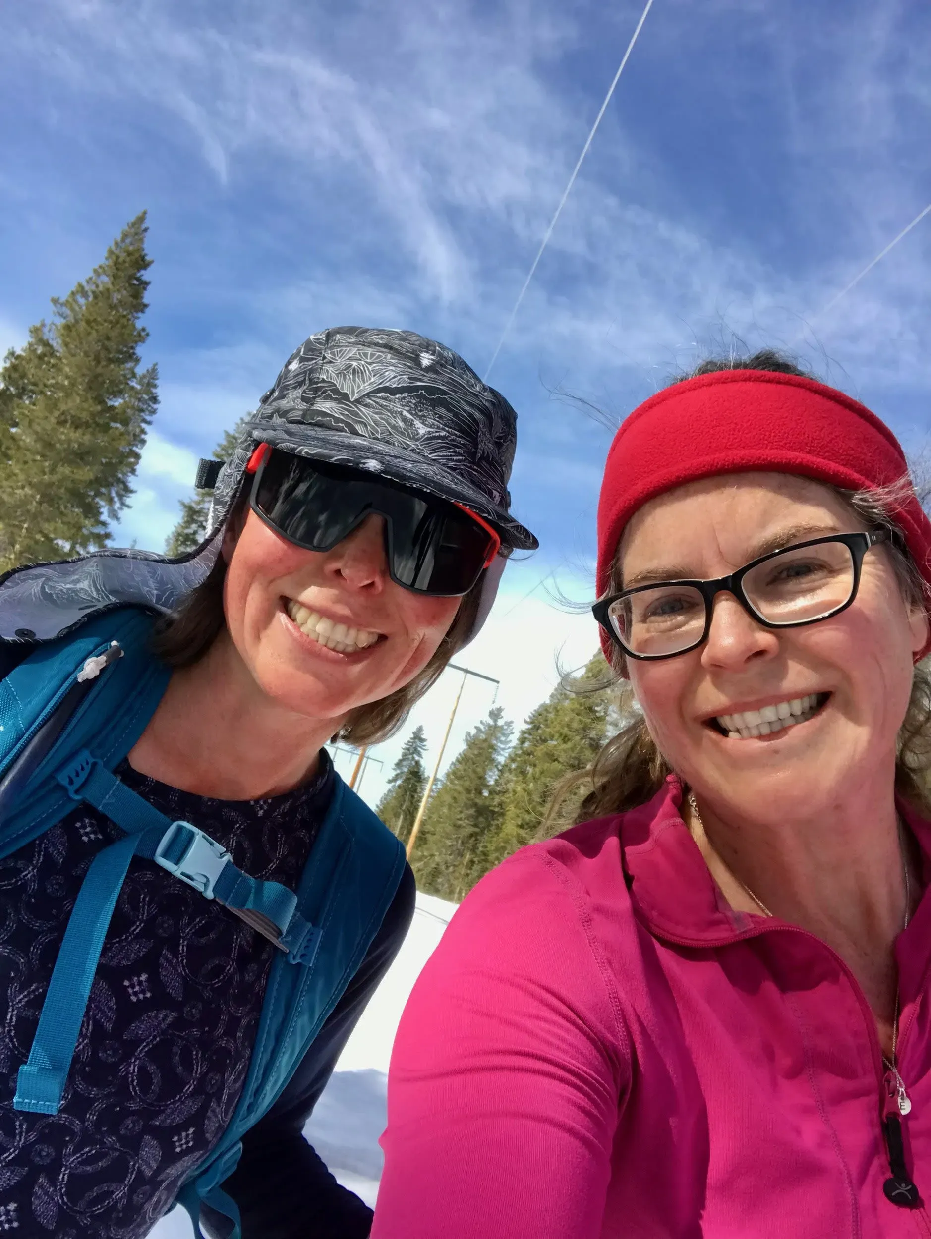 صورة تظهر امرأتين مبتسمتين ترتديان ملابس التزلج، في منطقة جبلية مغطاة بالثلوج، تعكس روح المغامرة والصداقات في رحلتهم إلى سييرا نيفادا.