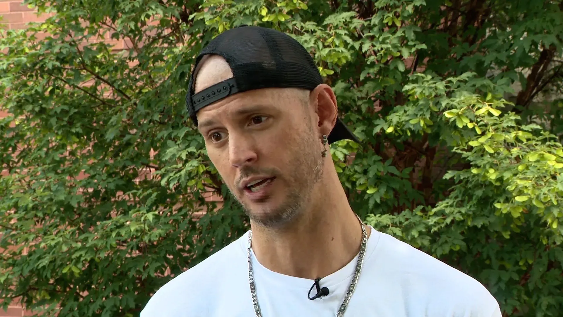 رجل يتحدث في حديقة، محاط بأشجار، يروي قصة إنقاذ كلب بيتبول ضائع ومساعدة شخصين في حالة طبية.