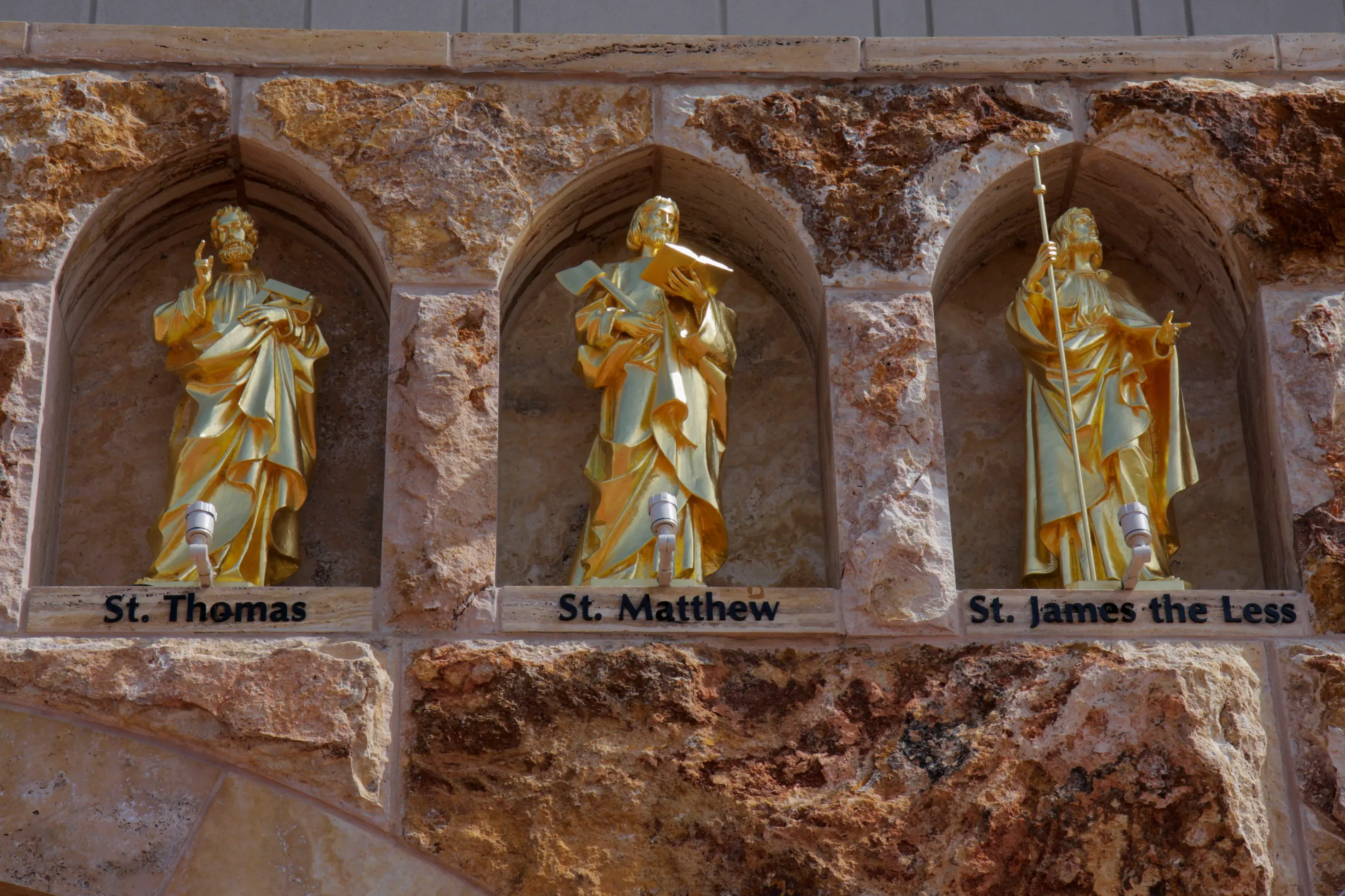 تمثالان ذهبيان للقديسين توما ومتى، والقديس يعقوب الأصغر، مثبتة في جدار حجري، تعكس أهمية الدين في المجتمع.