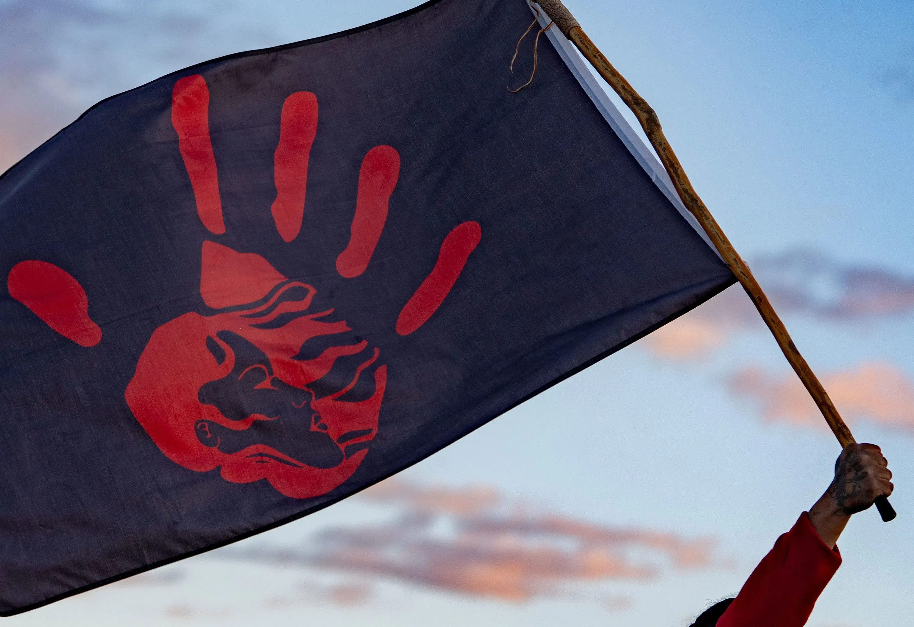 علم يحمل صورة يد حمراء ورمز وجه، يرمز إلى قضايا العنف ضد النساء والفتيات من السكان الأصليين في الولايات المتحدة.