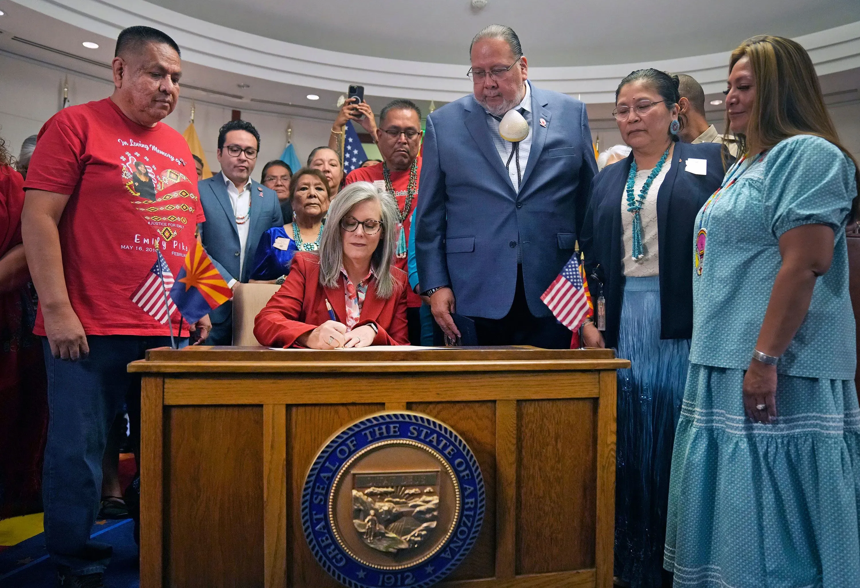 تجمع مجموعة من الأشخاص، بينهم قادة قبائل، حول طاولة أثناء توقيع قانون جديد في ولاية أريزونا، مما يعكس جهود مكافحة العنف ضد النساء والفتيات من السكان الأصليين.