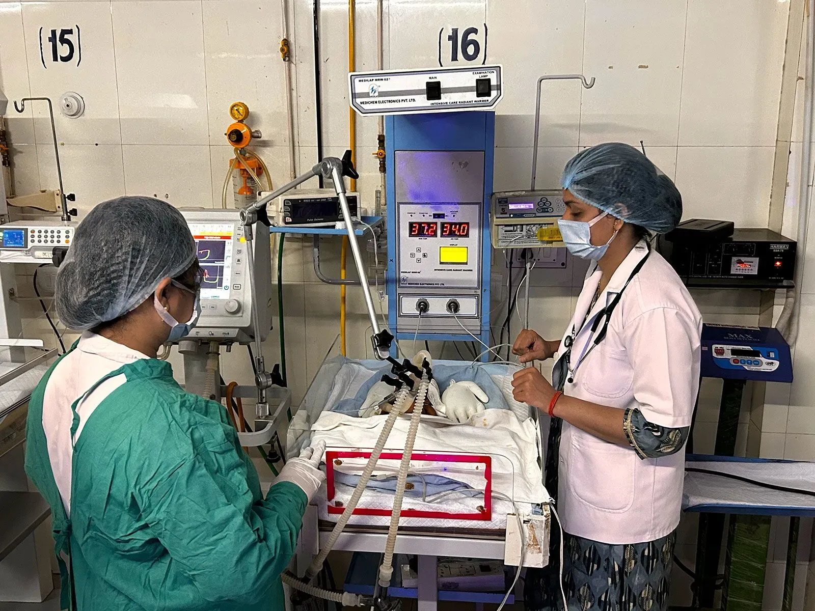 صورة لطبيبتين تعملان على إنقاذ طفلة حديثة الولادة في وحدة العناية المركزة، حيث تُظهر الأجهزة الطبية المستخدمة في رعايتها.