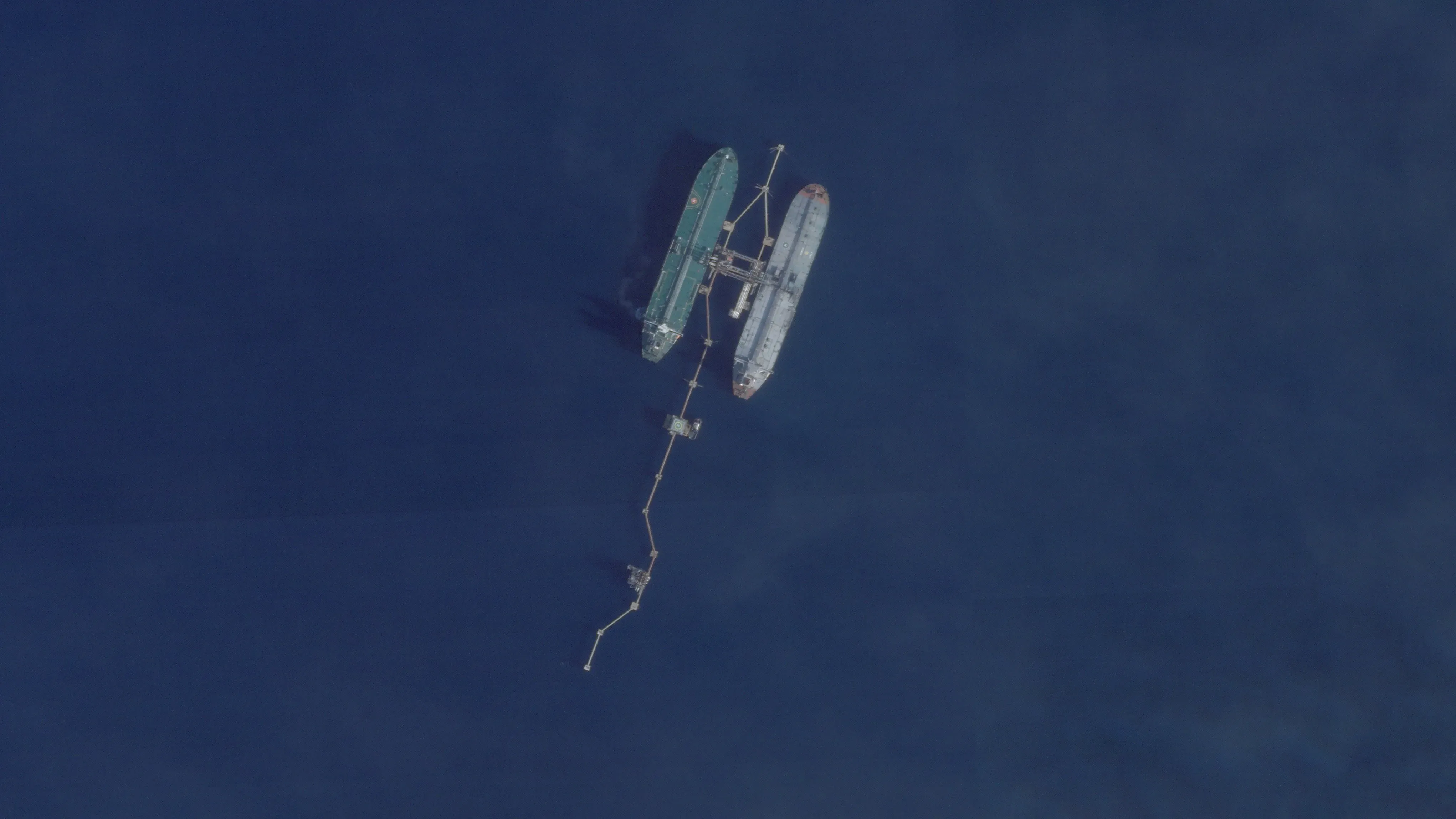 ناقلة نفط كبيرة في البحر، تظهر تفاصيل هيكلها الصدئ، بينما يتم توصيلها بسفينة أخرى عبر أنبوب، في سياق مطاردة أمريكية.