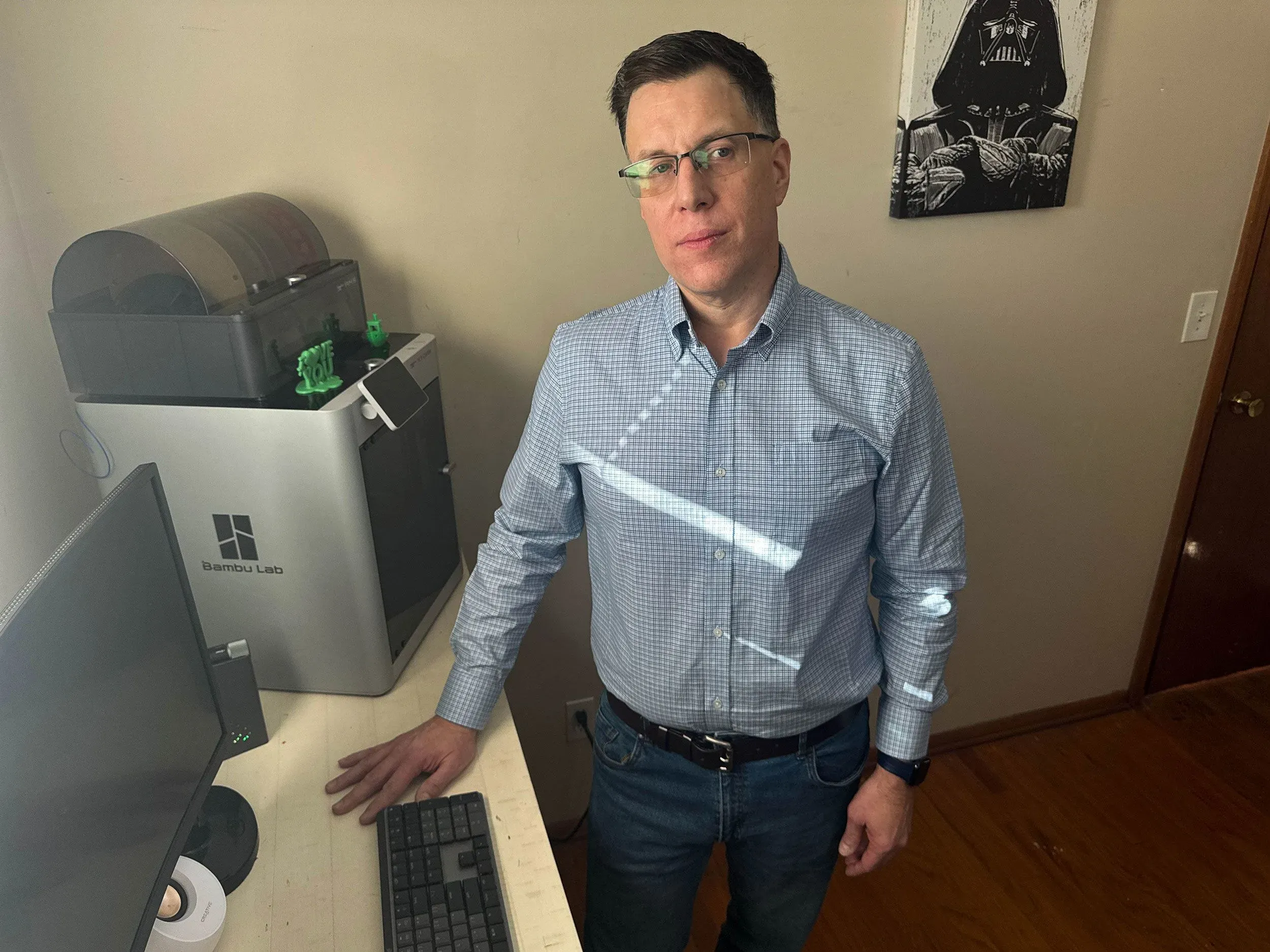 جو نوفاك يقف في غرفة عمله، محاط بأدوات التكنولوجيا، يعكس تجربة مؤلمة مع الاحتيال عبر الإنترنت.