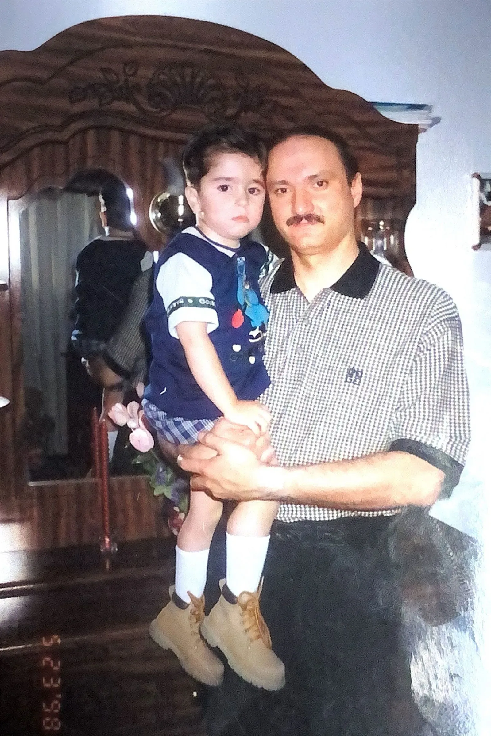 صورة تظهر والد وائل طرابيشي وهو يحمل ابنه الصغير، مع خلفية تعكس لحظات عائلية دافئة، تعبيرًا عن الحب والرعاية.