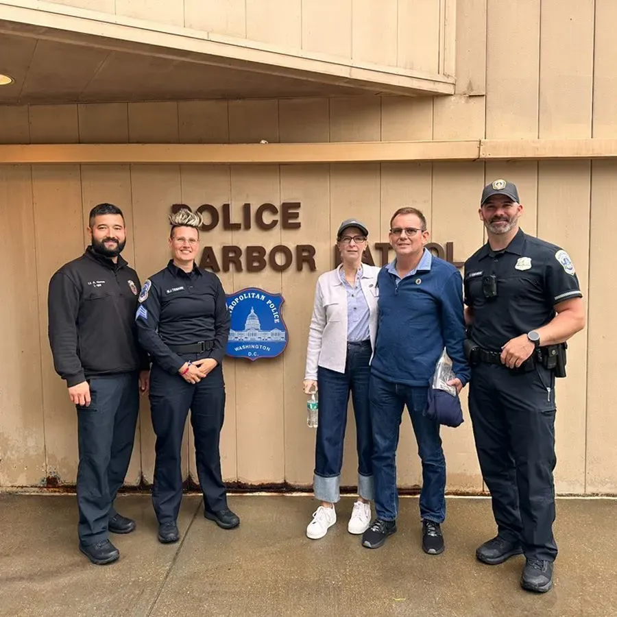 مجموعة من خمسة أشخاص يقفون أمام مركز شرطة الميناء في واشنطن، مع وجود علامة المركز خلفهم، في جو من التعاون والدعم.