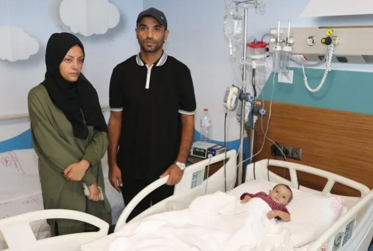 حامد وبسمة أبو زرقة يقفان بجانب سرير ابنتهما حبيبة في مستشفى أضنة، حيث تتلقى العلاج بعد معاناتها من سوء التغذية.