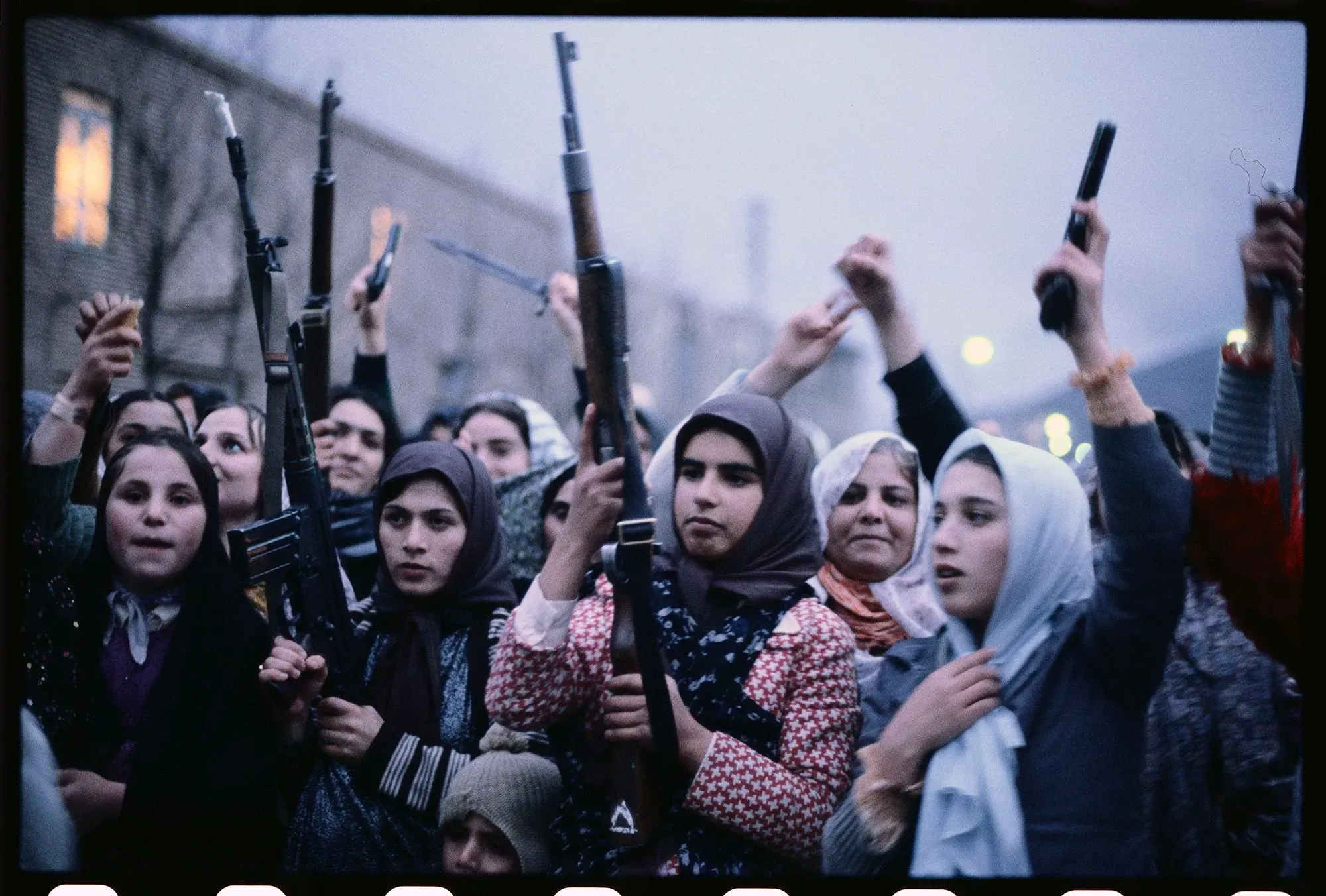 مجموعة من النساء الكرديات يحملن أسلحة، يعبّرن عن قوتهن وعزيمتهن في مواجهة التحديات، وسط أجواء من الاحتجاجات والمقاومة.