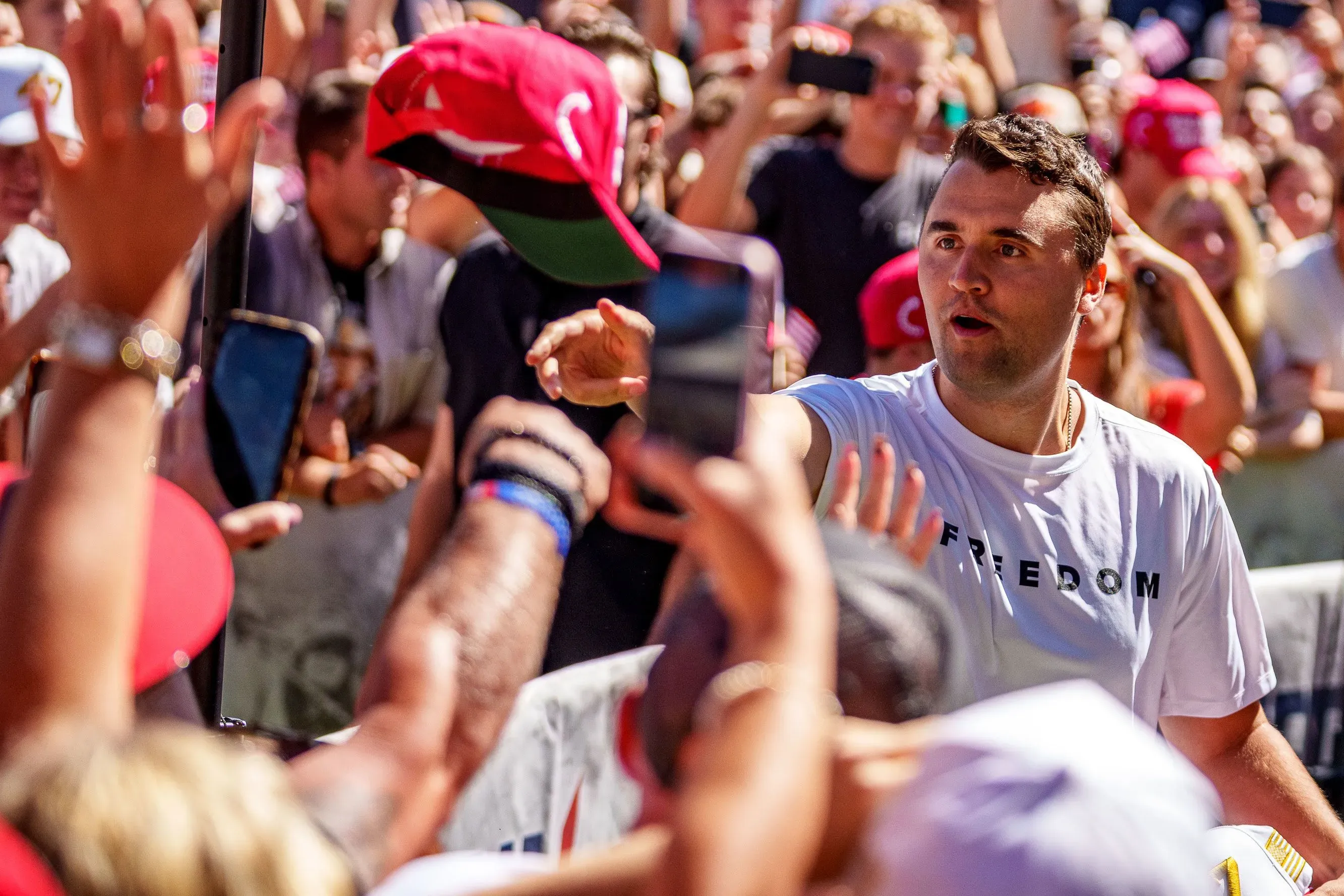 تجمع حاشد حول تشارلي كيرك، سفير ترامب، حيث يظهر الحضور يتفاعلون بحماس أثناء حدث سياسي، مما يعكس التوترات الحالية في السياسة الأمريكية.