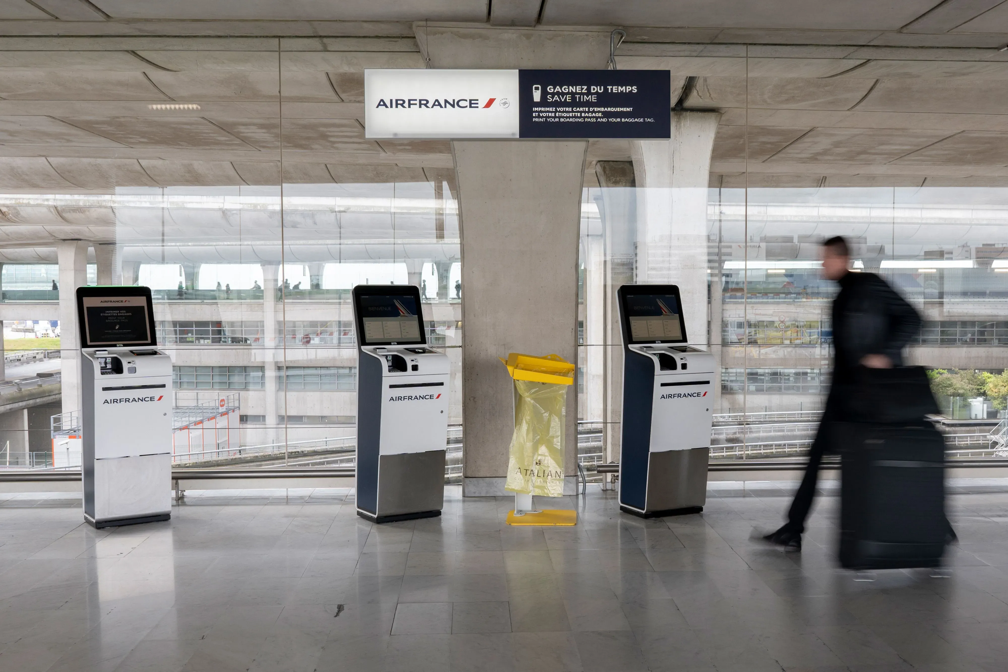 مكتب تسجيل الوصول لشركة Air France في مطار، مع مسافر يحمل حقيبة، يعكس تحديات السفر بسبب ارتفاع أسعار الوقود.