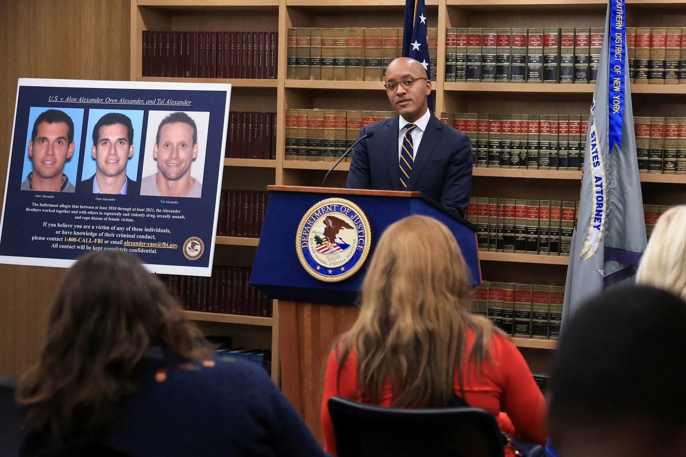 تظهر الصورة المدعي العام يتحدث في مؤتمر صحفي حول قضايا الاعتداء الجنسي ضد الأخوين ألكسندر، مع عرض صورهم خلفه.