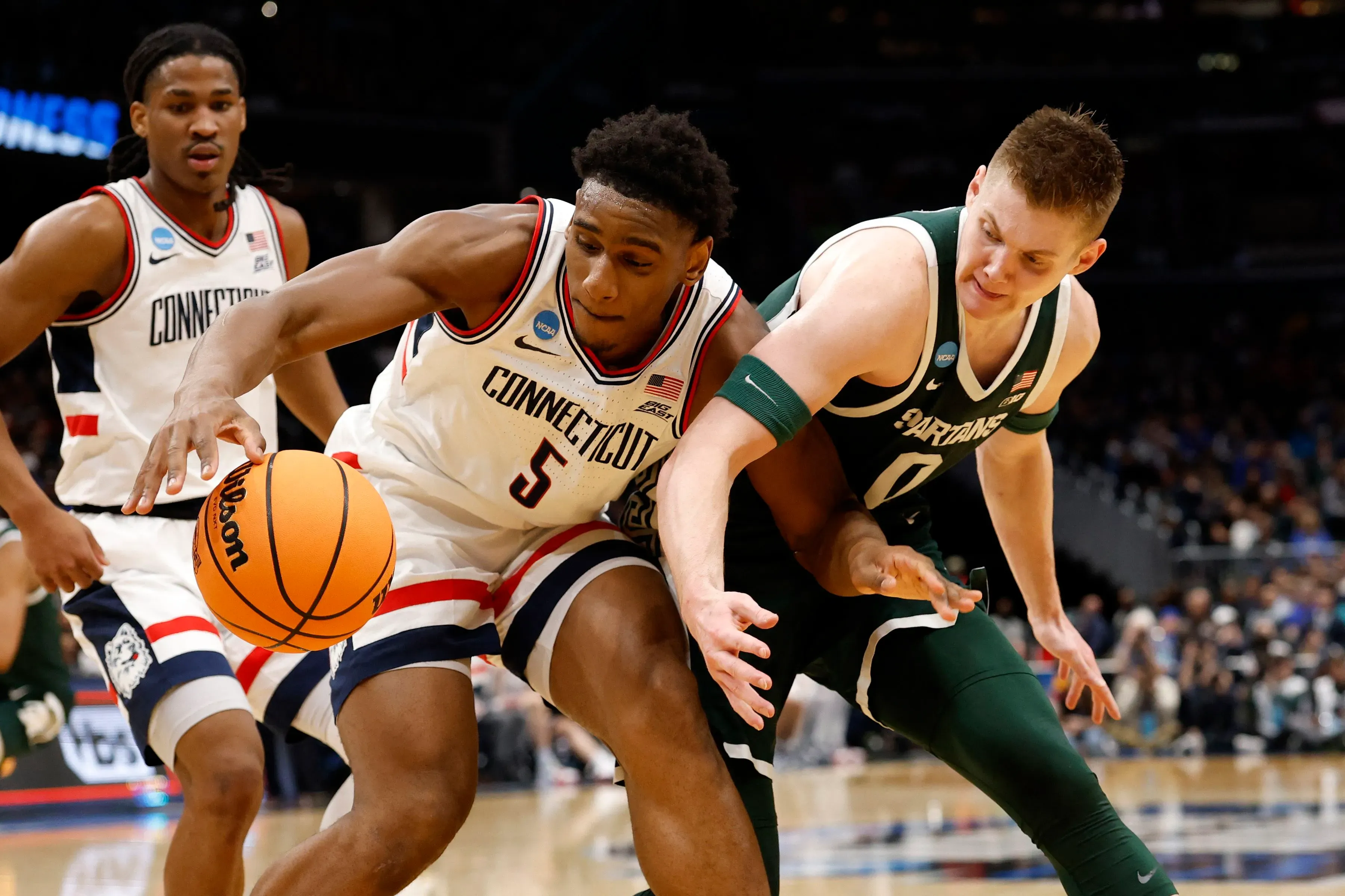 لاعبو كرة السلة يتنافسون على الكرة خلال مباراة NCAA، مع تعبيرات وجهية تعكس التوتر والضغط في لحظات حاسمة.