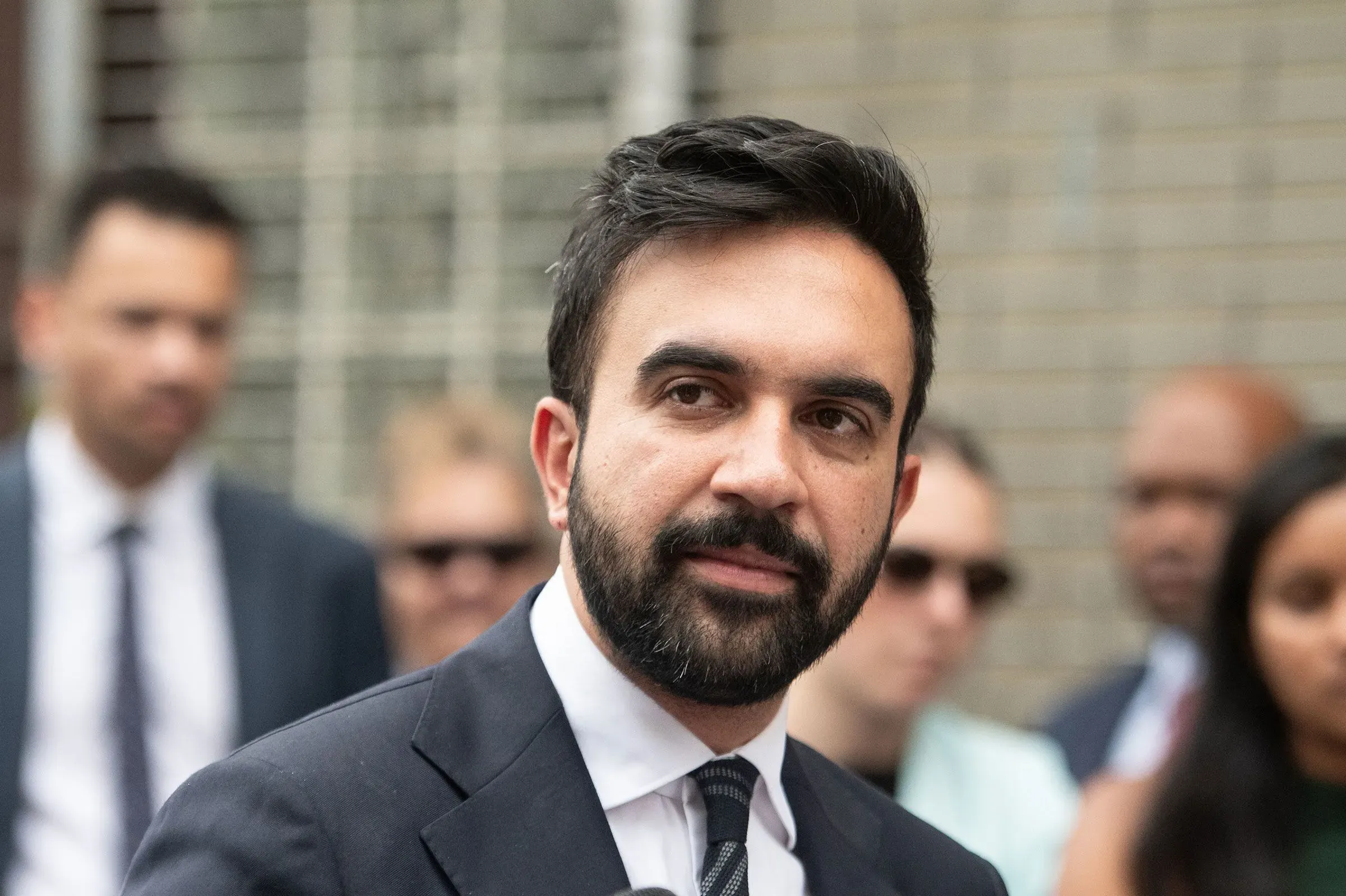 ممداني يتحدث في حدث عام، مع وجود مساعديه في الخلفية. تعكس تعابيره التوتر حول رد فعله على وفاة ضابط شرطة في مانهاتن.