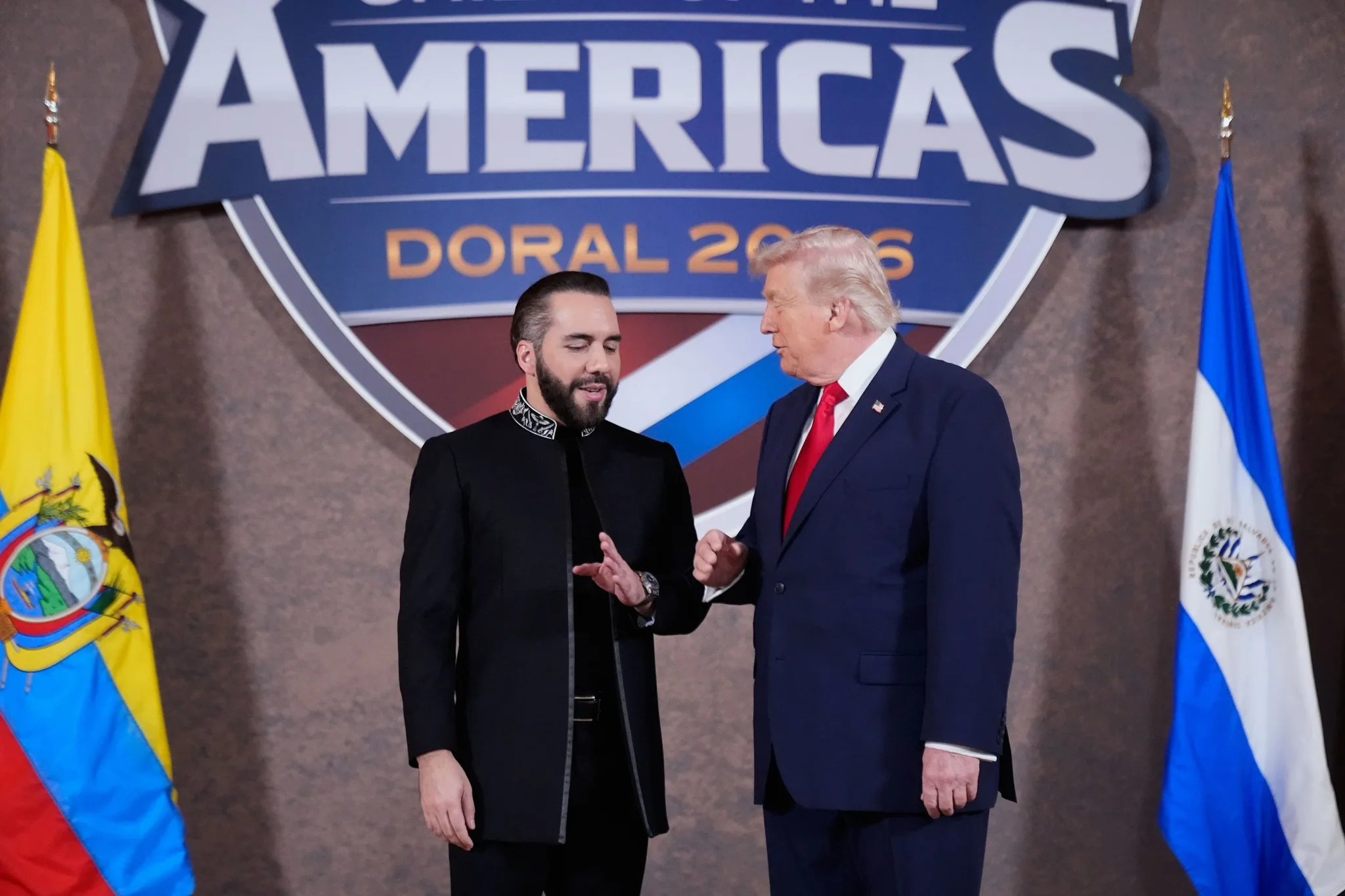 الرئيس الأمريكي السابق دونالد ترامب والرئيس السلفادوري نجيب بوكيلي يتحدثان خلال قمة الأمريكتين 2026 في دورال، مع وجود علمي السلفادور والإكوادور في الخلفية.