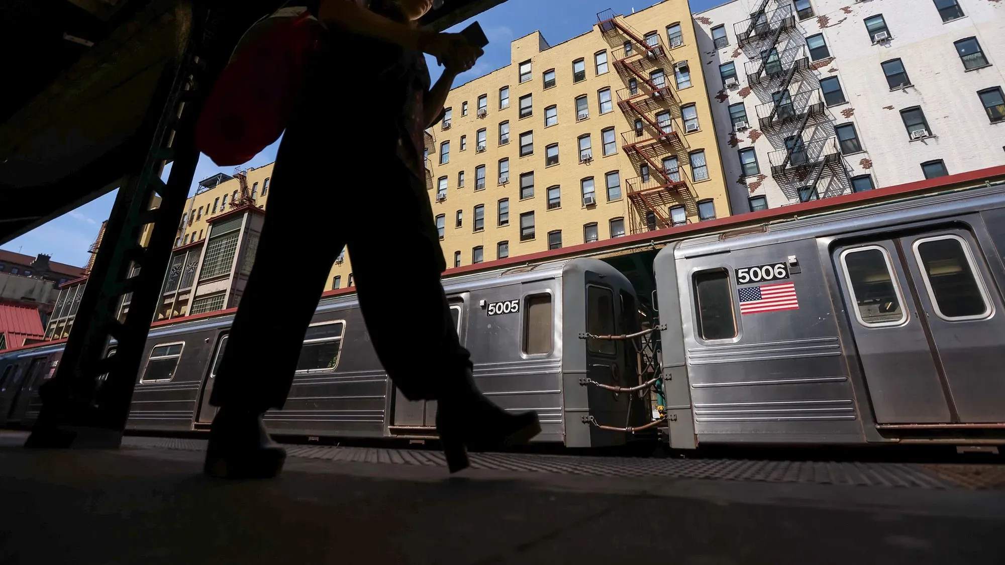 امرأة تسير على رصيف محطة المترو في مدينة نيويورك، بينما يظهر قطار متوقف في الخلفية، مما يعكس تحديات العمل للنساء في السوق.