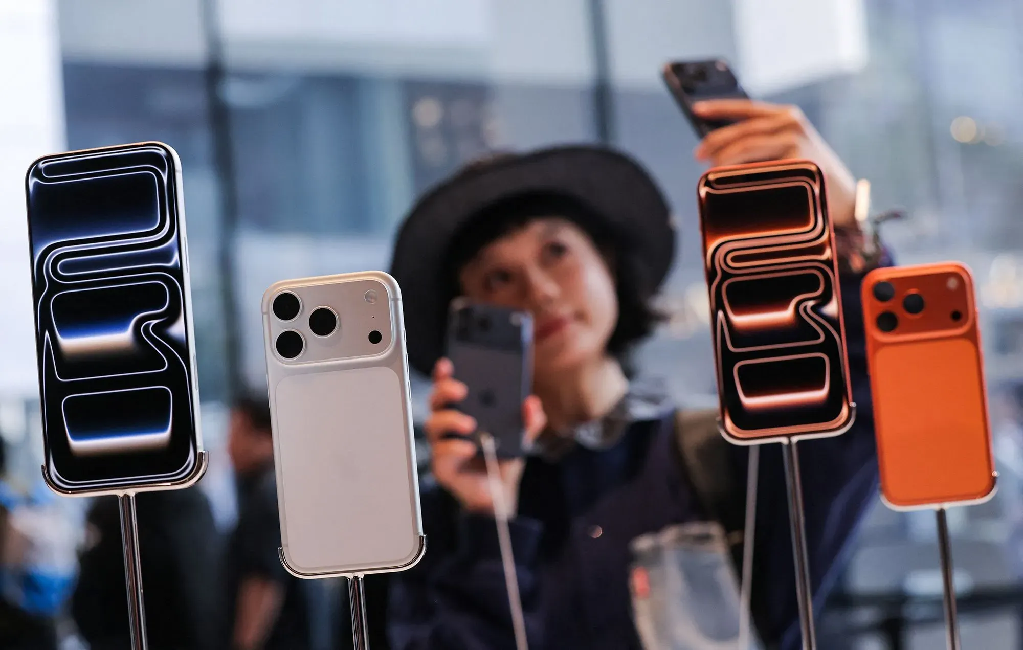 عرض لأربعة هواتف ذكية جديدة من Apple مع امرأة تلتقط صورة، مما يعكس تطور الشركة في مجال التكنولوجيا المحمولة.