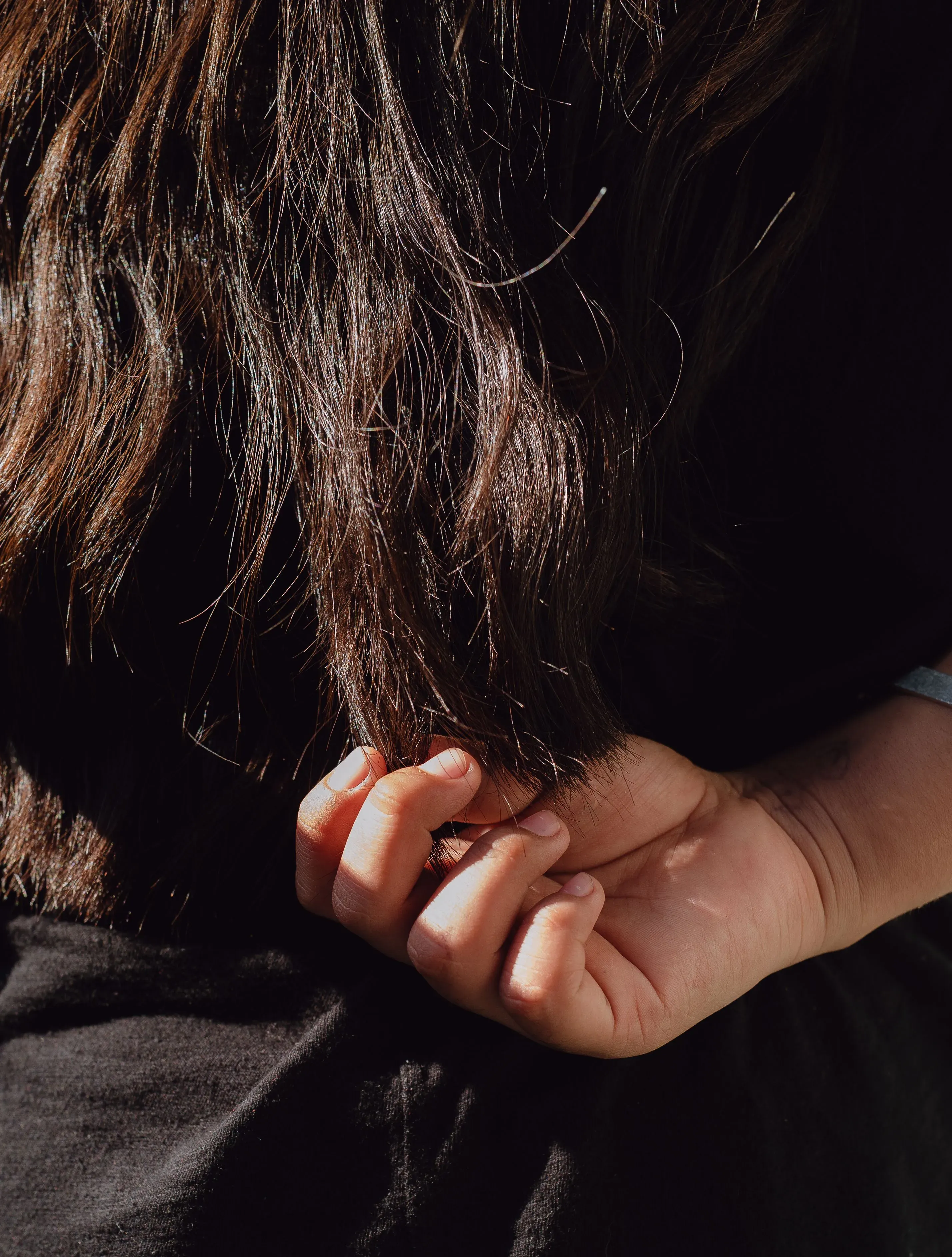 يد تحمل خصلات من الشعر الطويل، تعبر عن شعور الحزن والافتقاد، في سياق مأساة انفصال الأطفال عن عائلاتهم بسبب سياسات الهجرة.