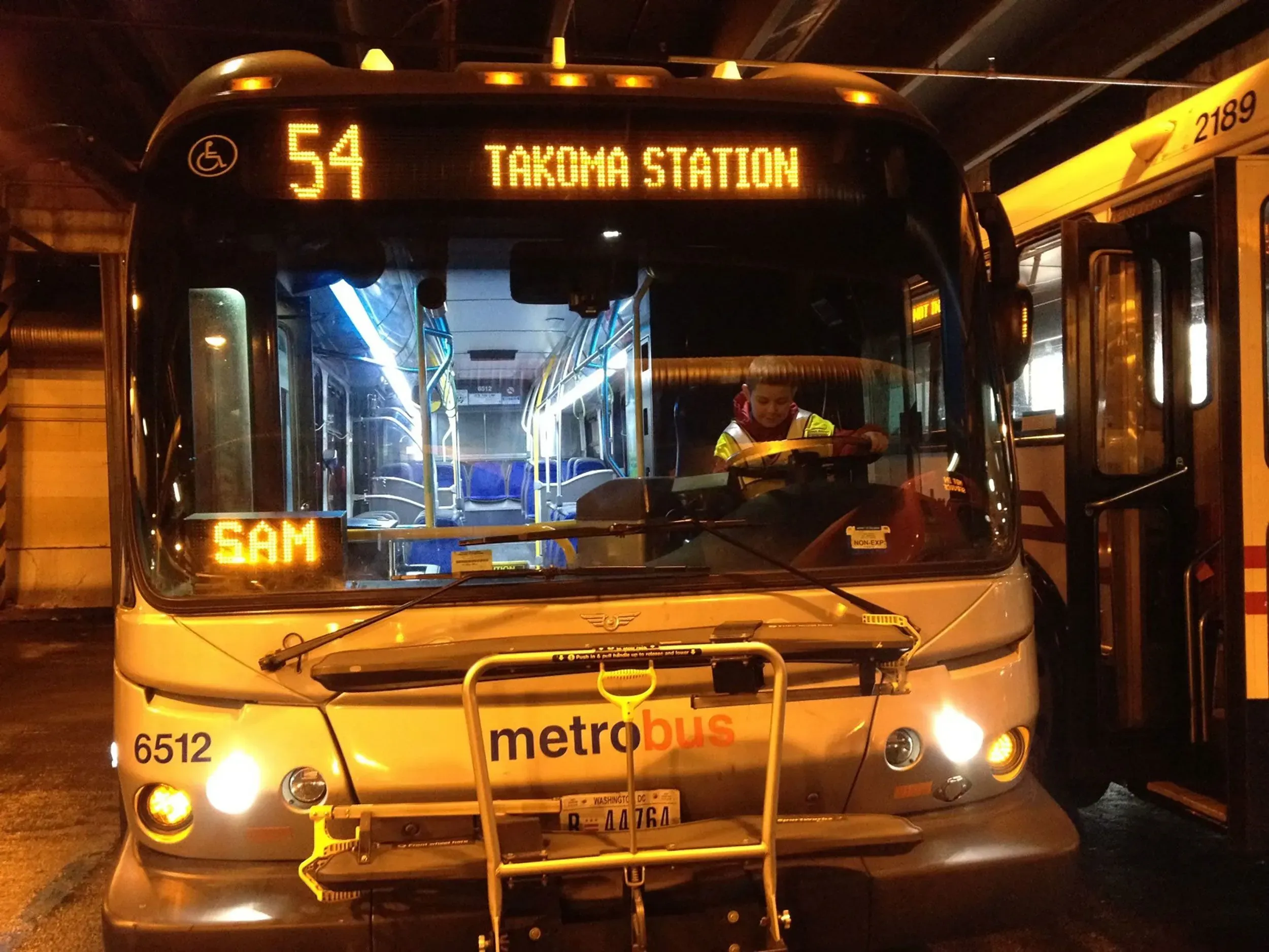 حافلة مترو تحمل رقم 54 متوقفة في محطة تاكوم، مع سائقها سام الذي يبتسم داخل المقصورة.