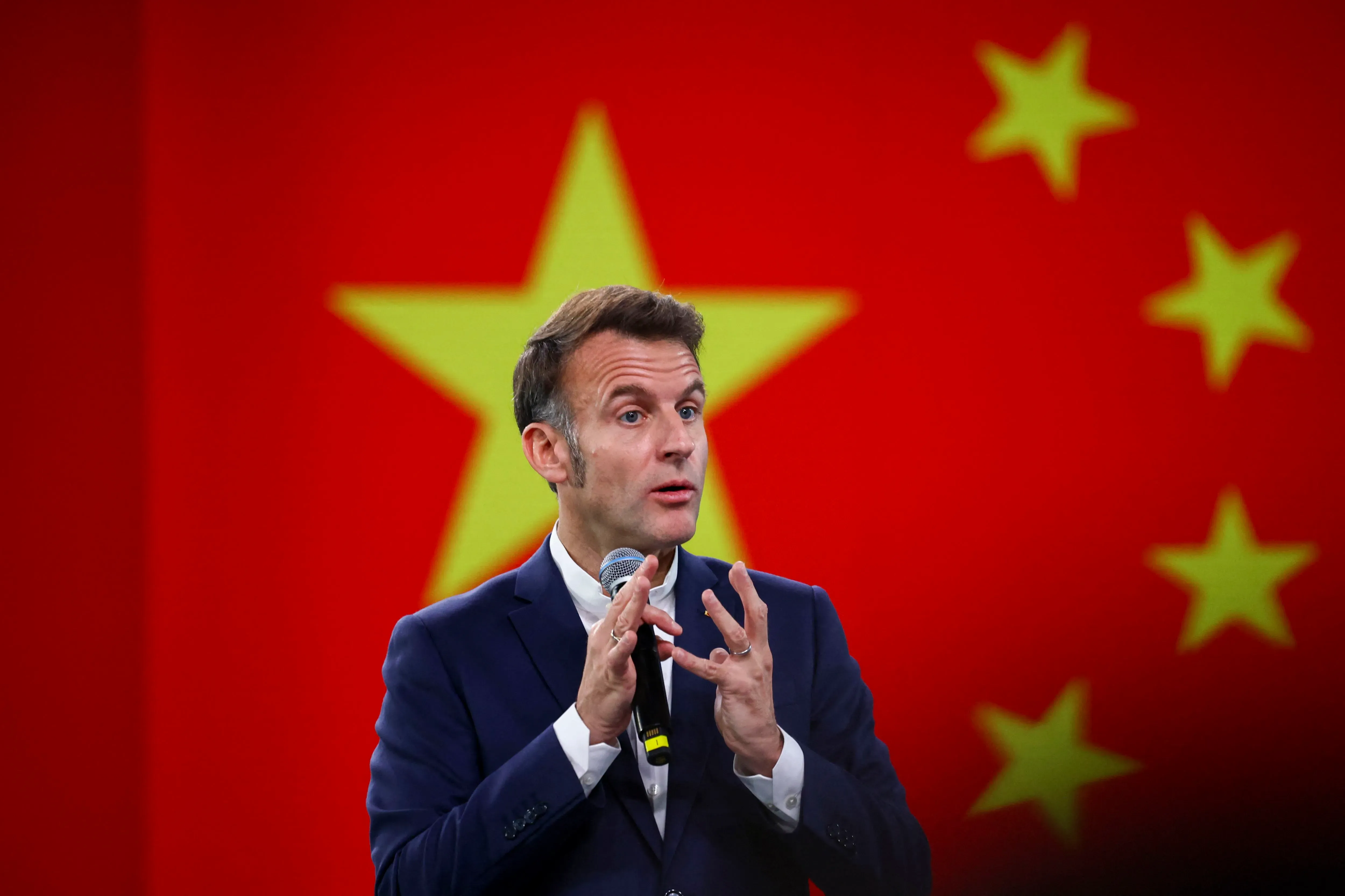 إيمانويل ماكرون يتحدث أمام علم الصين، معبرًا عن أهمية العلاقات الاقتصادية بين الصين والدول الغربية.