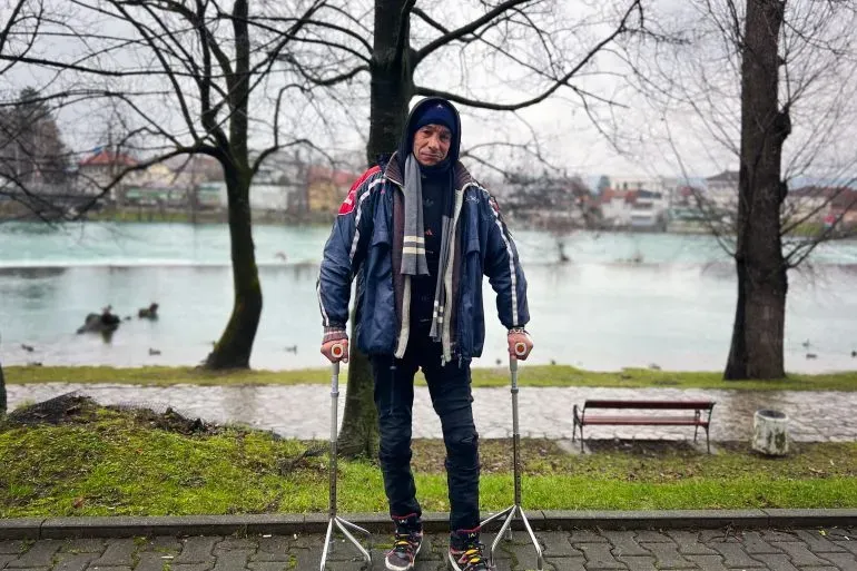 رجل مسن يستخدم عكازين في حديقة ببيهاتش، البوسنة، يعبر عن معاناته كلاجئ يسعى للوصول إلى أوروبا وسط ظروف صعبة.