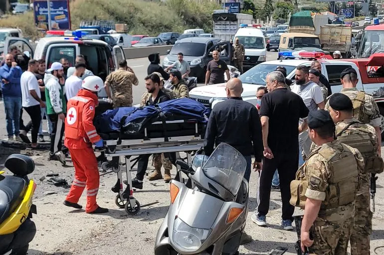 مشهد من موقع الهجوم في لبنان، حيث يقوم المسعفون بنقل جرحى إلى سيارات الإسعاف وسط تجمع حشود من الناس والمركبات.