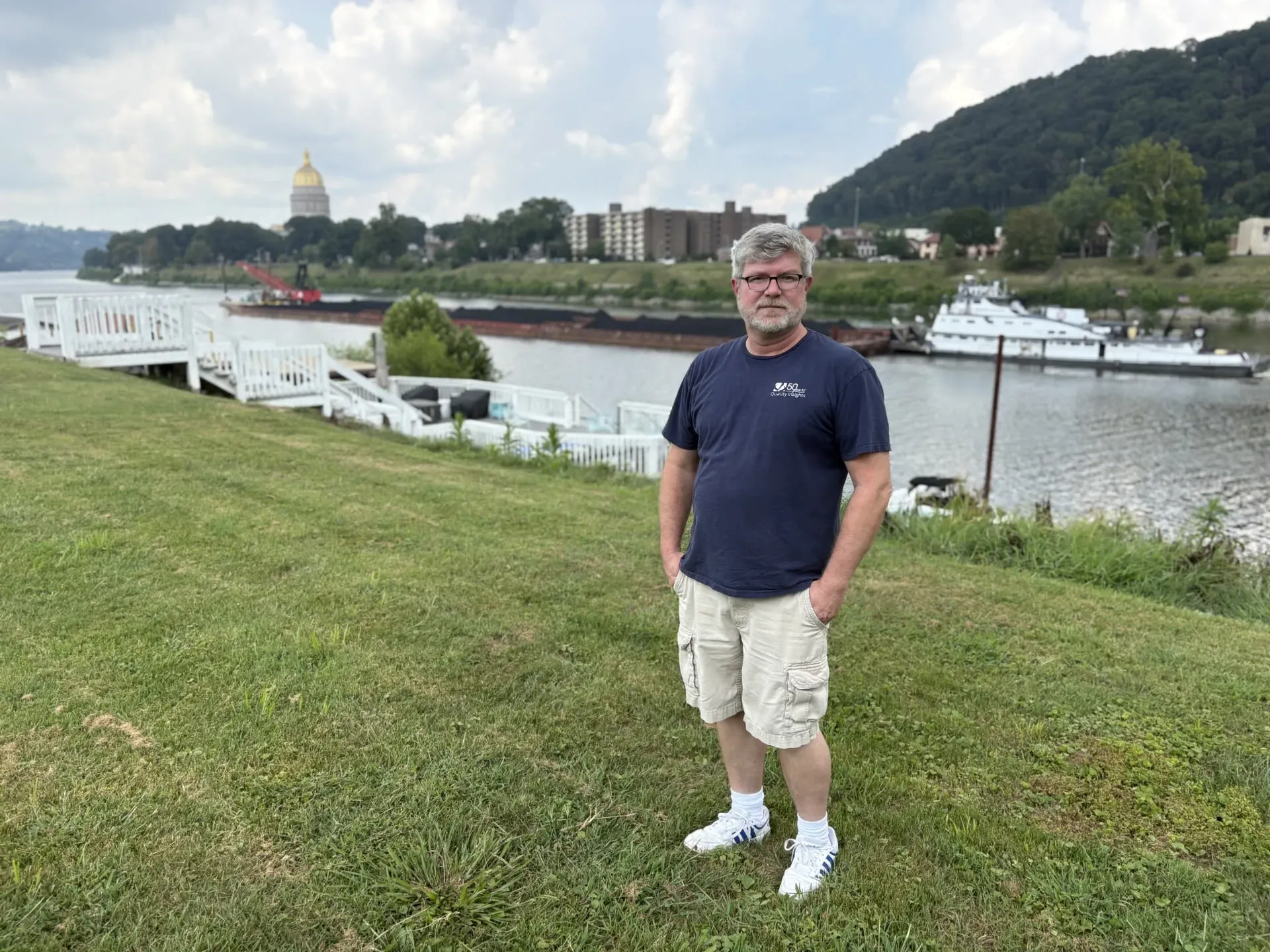 رجل يقف على ضفة نهر تينيسي، مع خلفية تظهر المستشفى والمباني المحيطة، في سياق مخاطر الفيضانات.