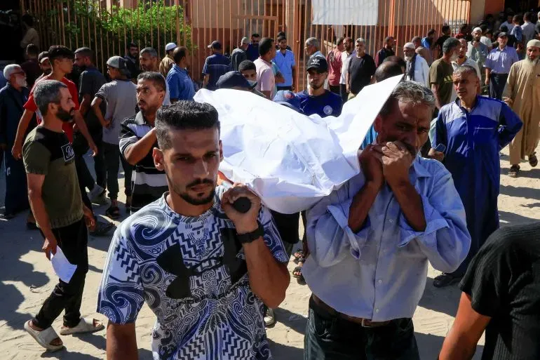 مواطنون يحملون جثمان أحد الضحايا في خان يونس، بعد مقتل 21 فلسطينيًا في تدافع أثناء توزيع المساعدات الإنسانية.