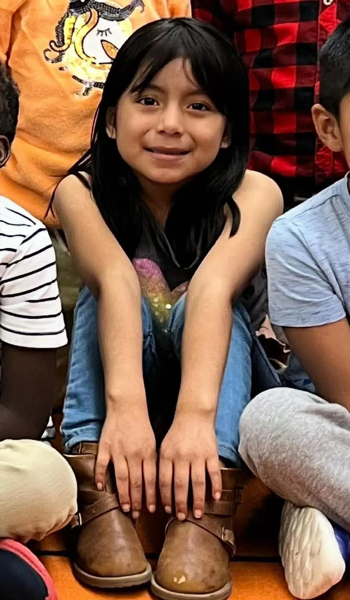 إليزابيث زونا كايساغوانو، فتاة تبلغ من العمر 10 سنوات، تجلس مبتسمة بين زملائها في المدرسة، تعكس براءتها وسط الأوضاع الصعبة.