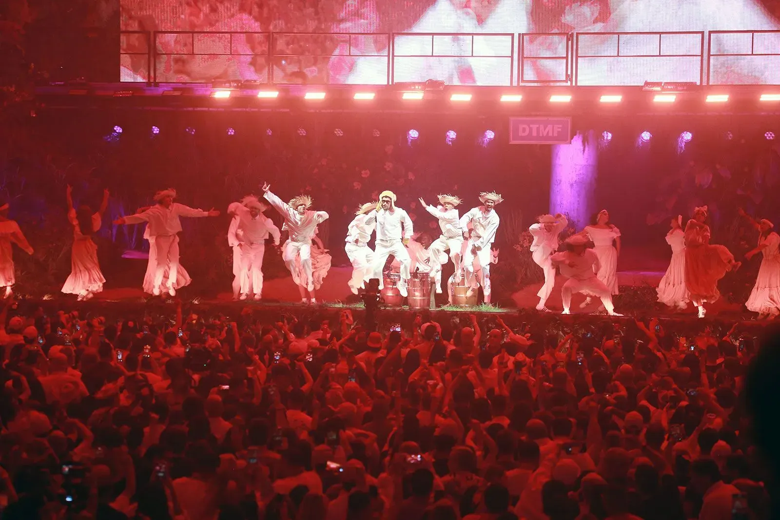 عرض موسيقي لباد باني في بورتوريكو، حيث يشارك الراقصون في أداء مفعم بالحيوية أمام جمهور كبير، مع أجواء احتفالية تعكس الثقافة البورتوريكية.