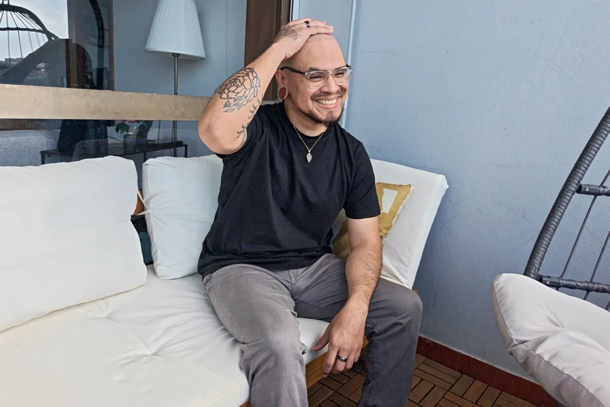 رجل مبتسم يجلس على أريكة، يمسح رأسه الأملس بعد حلاقة شعره، يعكس شعور الارتياح بعد مواجهة تساقط الشعر.