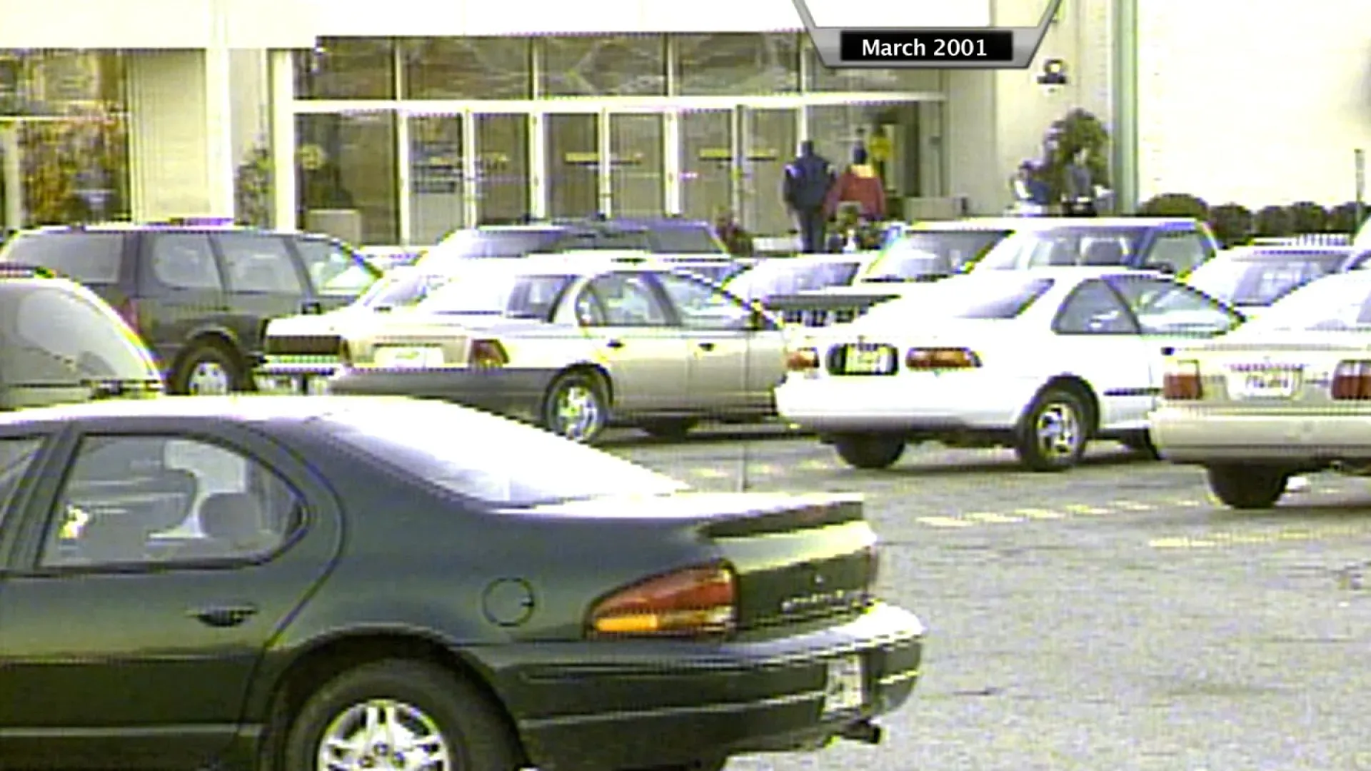 صورة لموقف سيارات مزدحم أمام متجر في مارس 2001، حيث يظهر عدد من السيارات بألوان وأشكال متنوعة، مما يعكس الحياة اليومية.