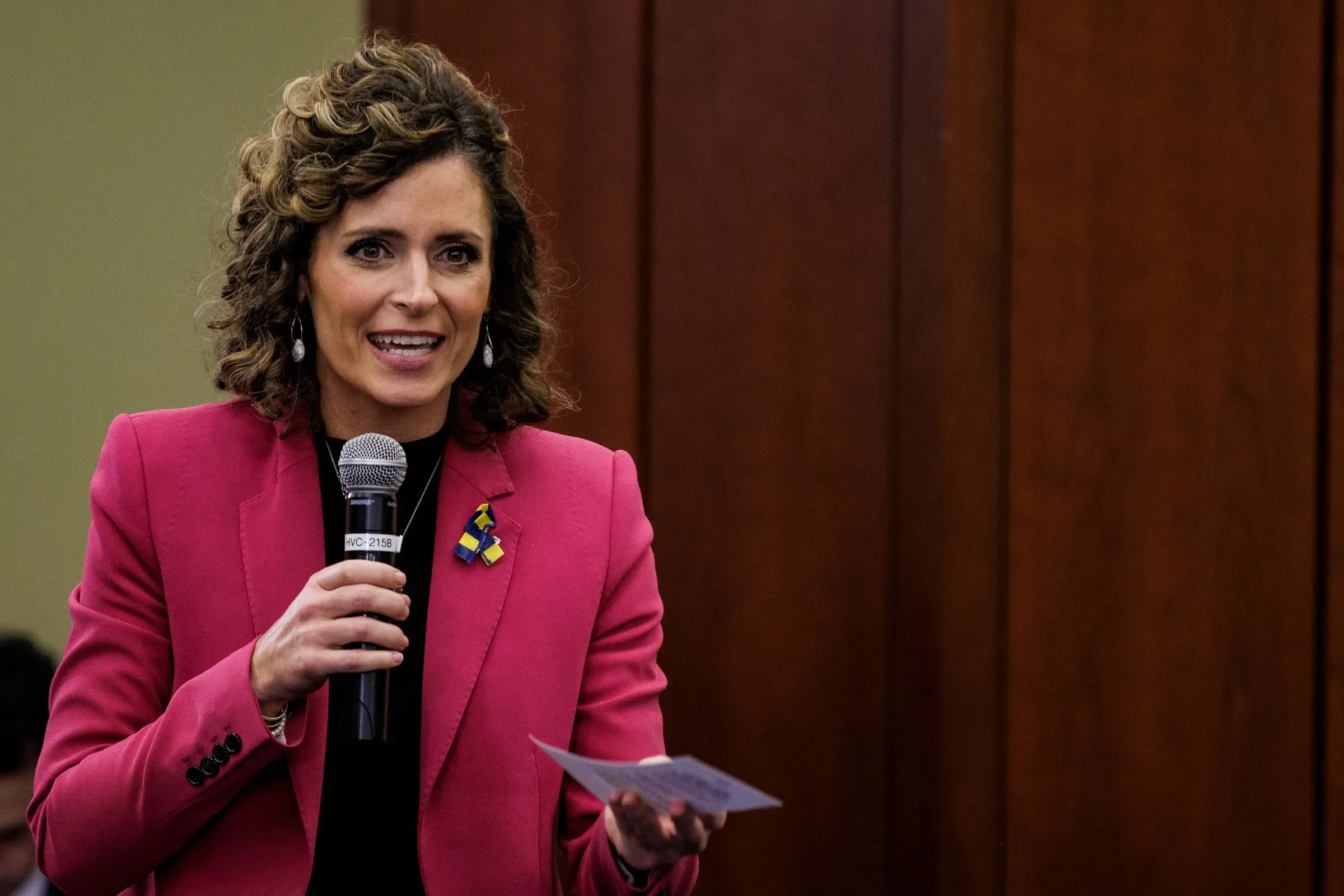 السيناتور كيسي مينز تتحدث أمام لجنة في الكونغرس، مرتدية سترة وردية، مع ميكروفون في يدها، تعبر عن وجهات نظرها حول اللقاحات.