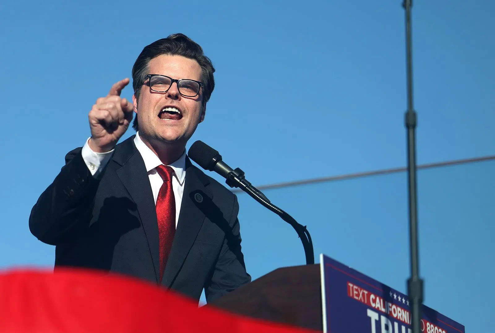 مدعي عام يتحدث بحماسة خلال تجمع سياسي، مع التركيز على قضايا حرية التعبير وخطاب الكراهية، وسط تفاعل جماهيري.