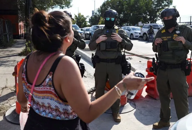 امرأة تتحدث مع عناصر من دوريات الحدود الأمريكية خلال احتجاج في شيكاغو، حيث تشهد المدينة توترات بين المتظاهرين ووكالة إنفاذ قوانين الهجرة.