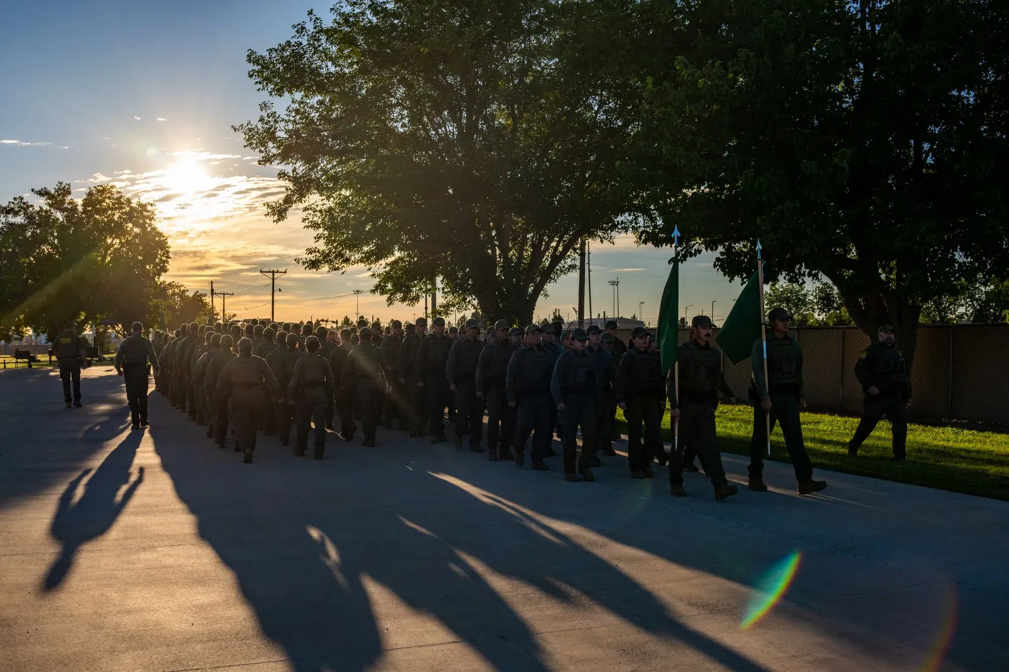 مجموعة من المجندين في أكاديمية حرس الحدود في نيو مكسيكو، يرتدون زيهم الرسمي، أثناء التفتيش الصباحي تحت أشعة الشمس.