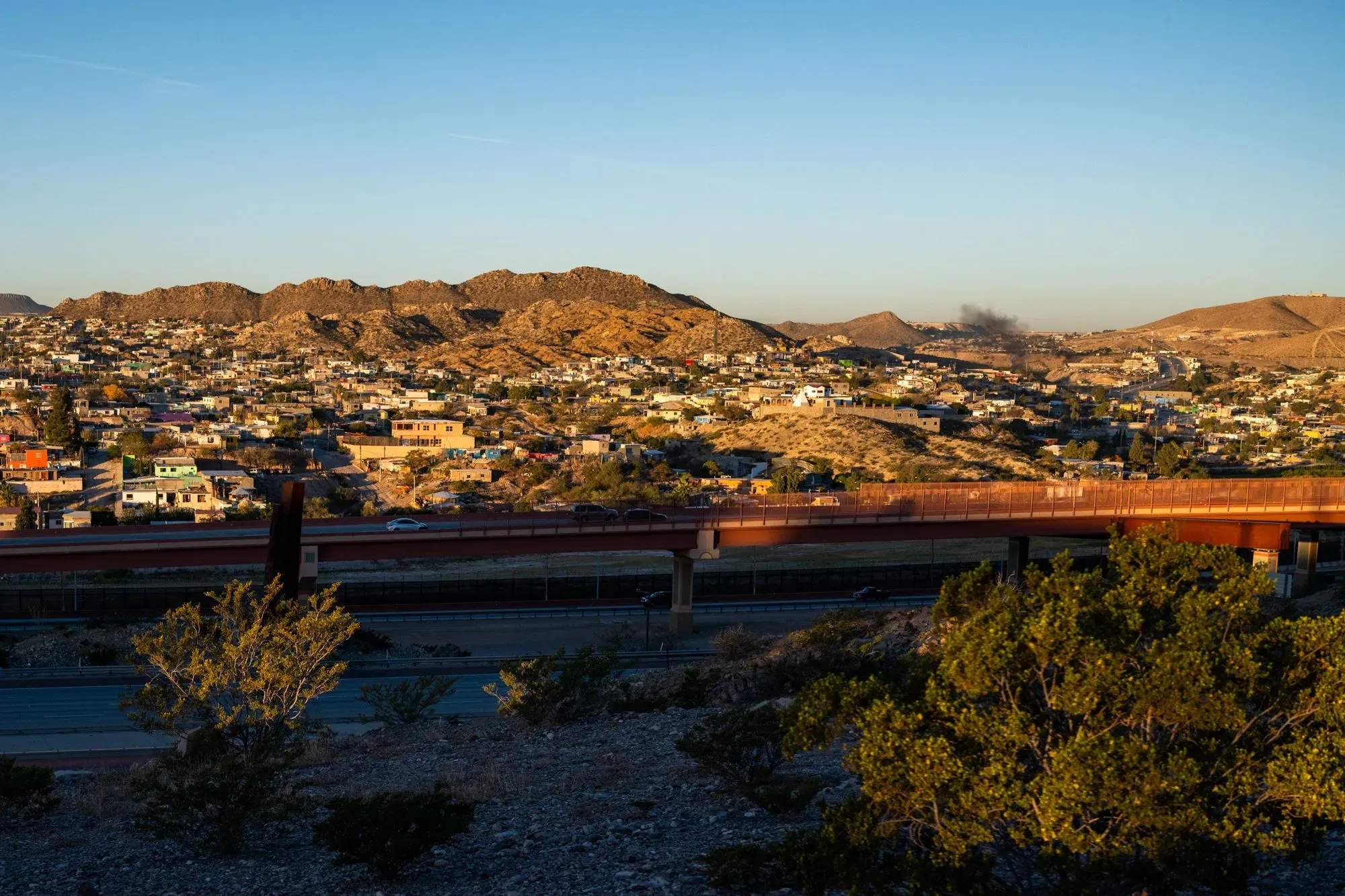 صورة تظهر الحدود بين الولايات المتحدة والمكسيك في نيو مكسيكو، مع تلال وصخور في الخلفية، تعكس المشهد المحيط بأكاديمية حرس الحدود.