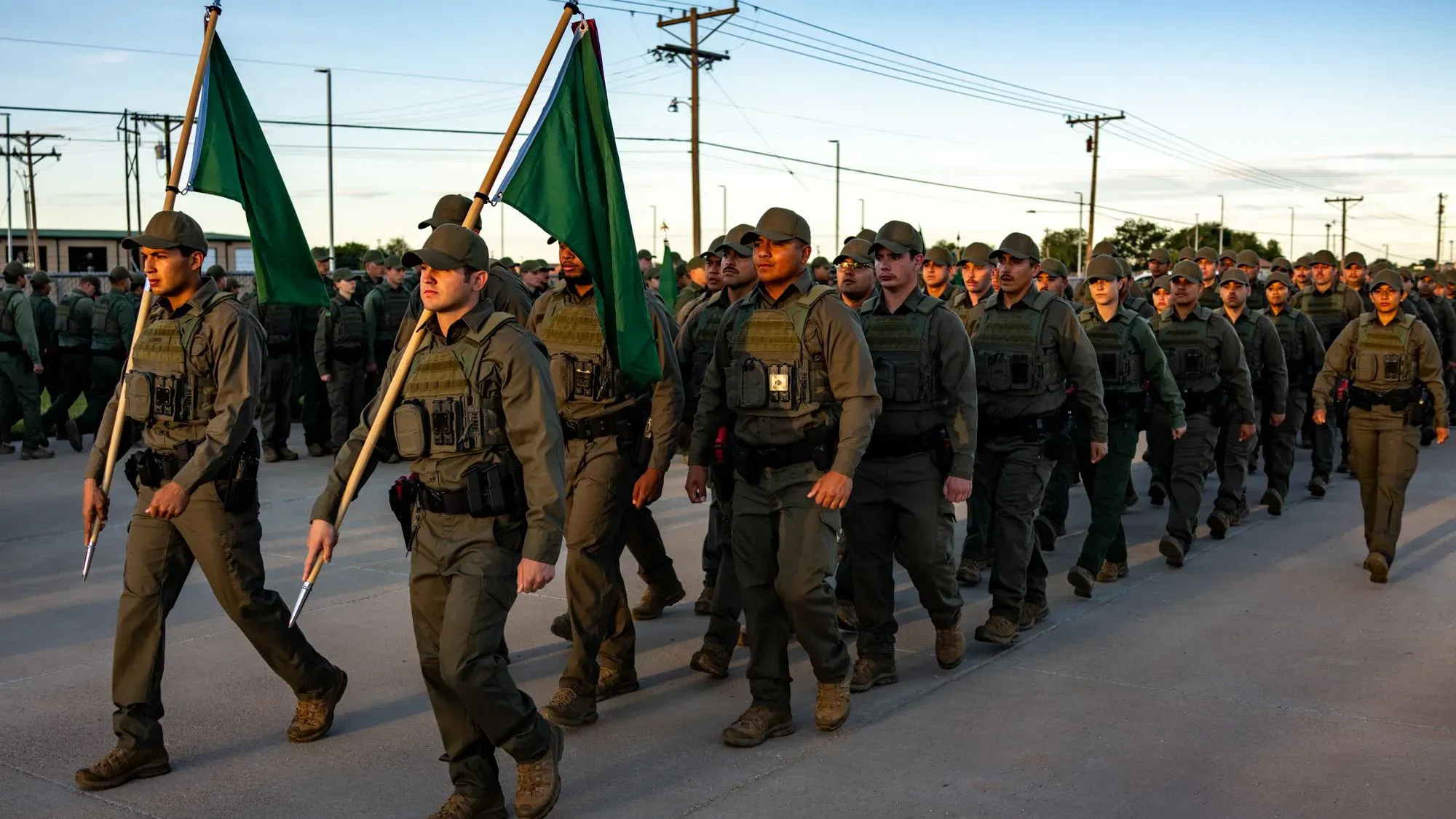 مجموعة من المجندين في أكاديمية حرس الحدود الأمريكية يرتدون زيهم الرسمي، يحملون الأعلام، خلال تفتيش الصباح في نيو مكسيكو.